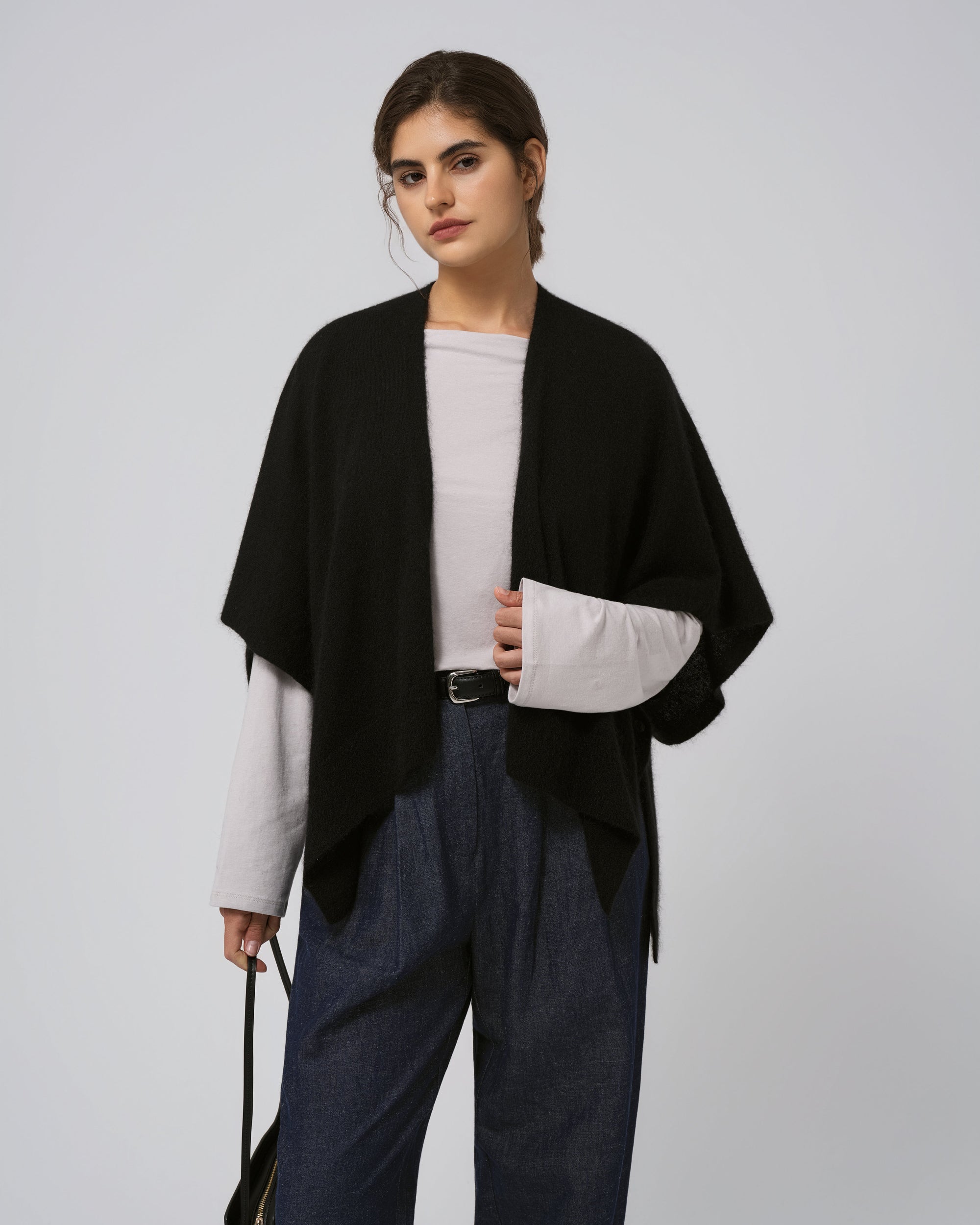 Model wearing Juana Cashmere Cape in black (wool–cashmere–hemp knit), showing fluid drape and sculptural silhouette.
