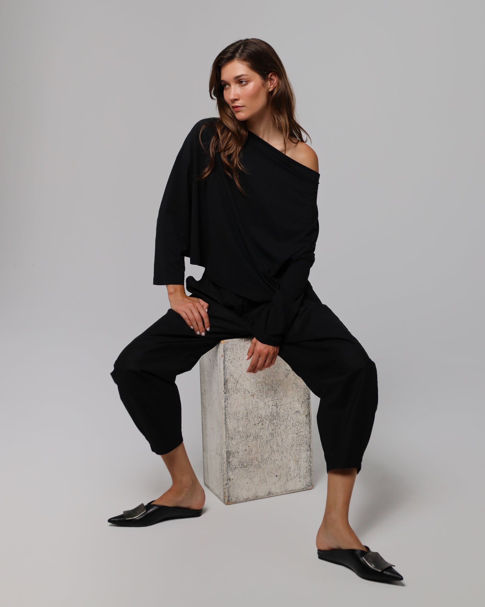 Woman wearing Juana Hemp Essentials Off The Shoulder Top in black hemp–Tencel™ blend, styled for sustainable everyday wear.