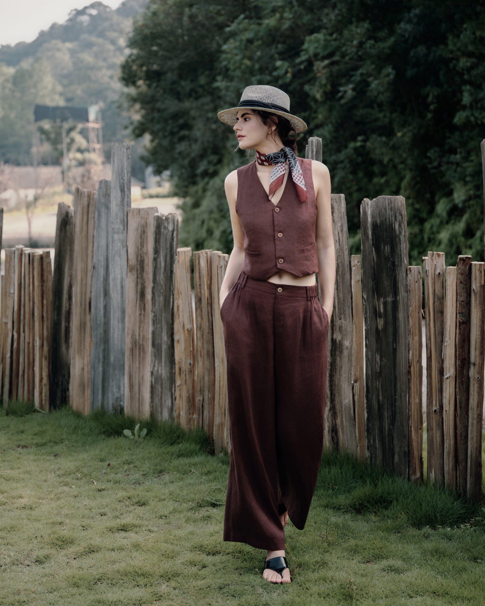 Walking on a grass in vest expresso and pants expresso over white tee; 100% hemp set with natural drape.