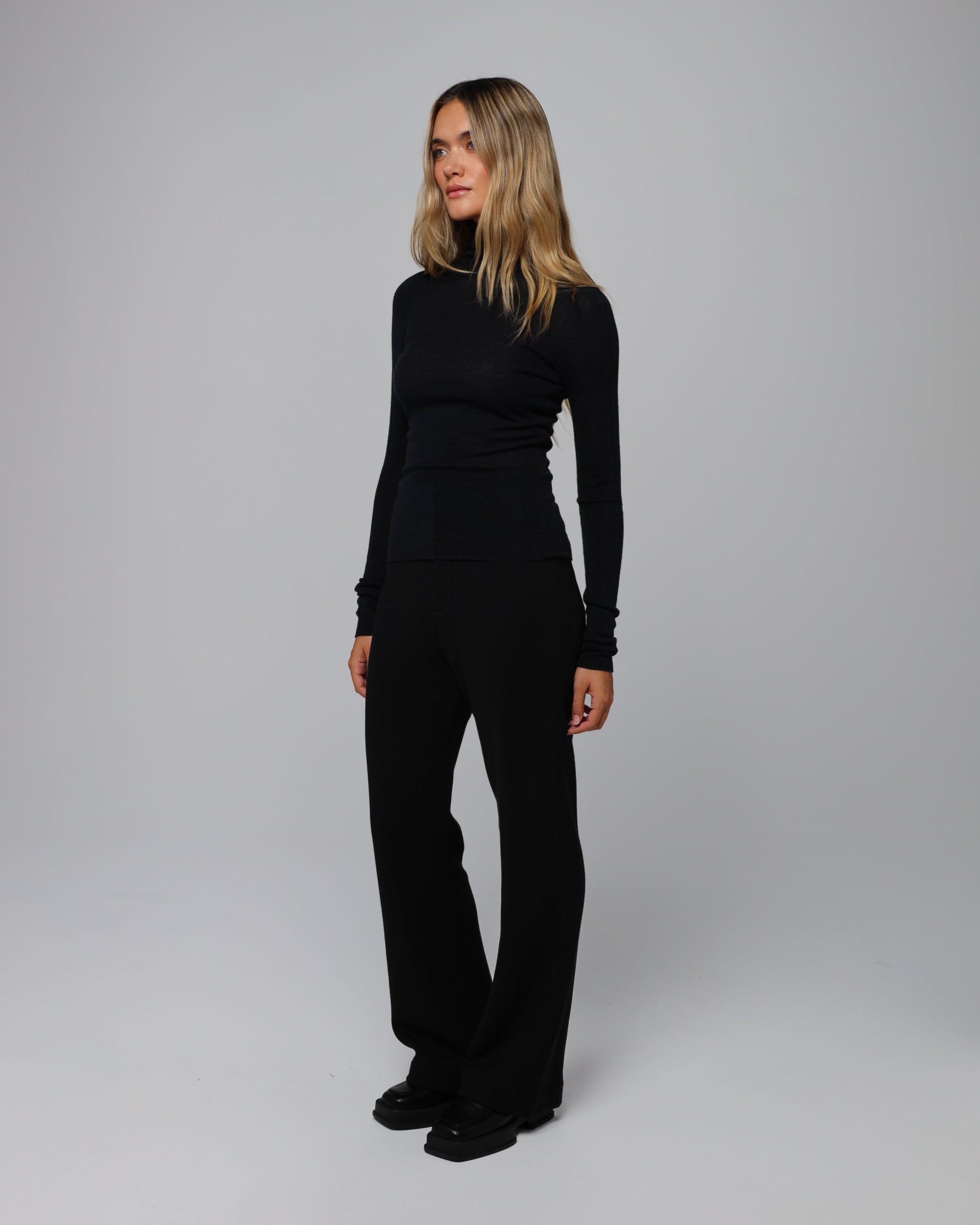 Model wearing Ossa Turtleneck (black) solo with tailored trousers for minimalist polish.
