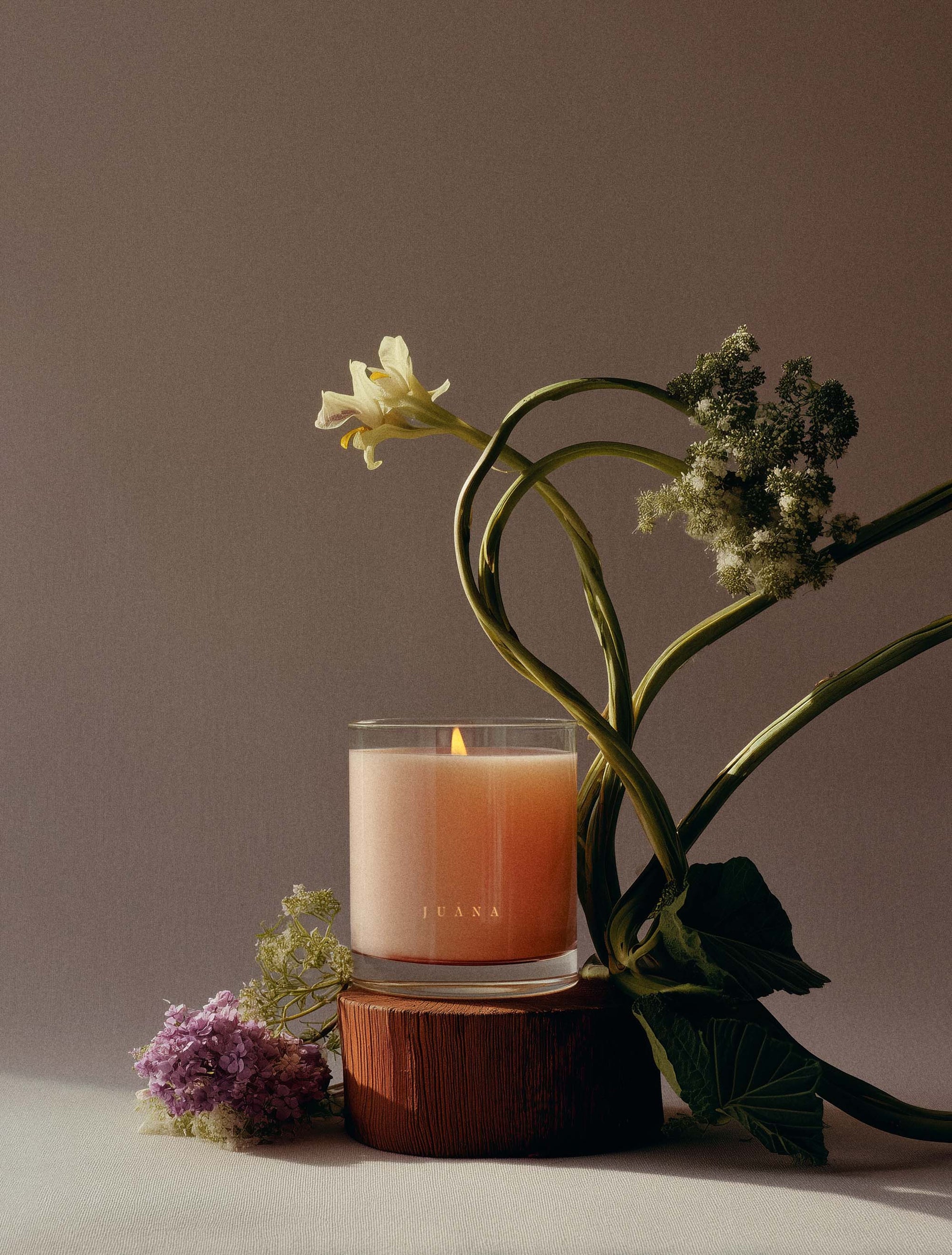 Juana Bergamot + Sativa Uplift apothecary medium candles beside a flower in vase, vegan, eco-friendly.