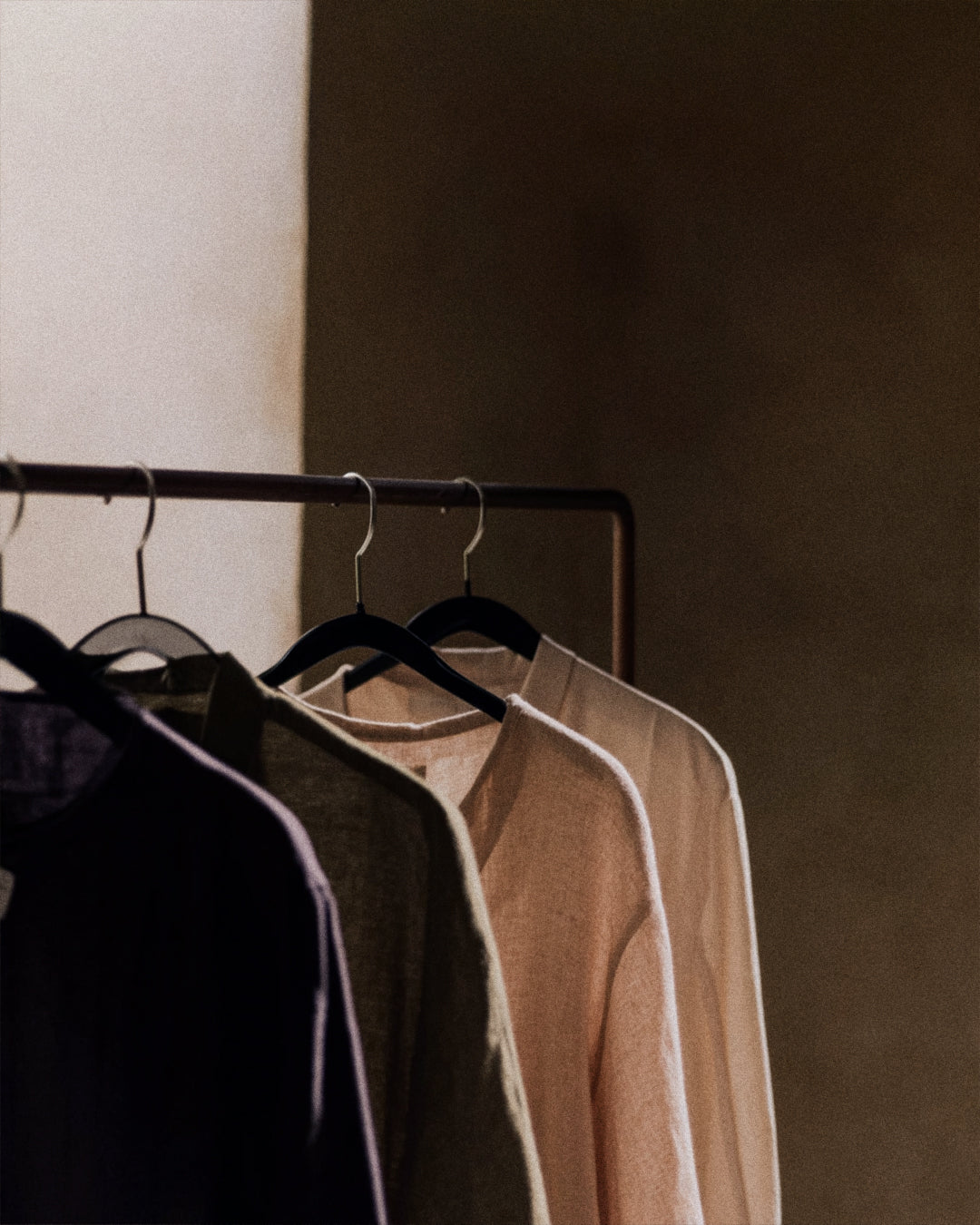 Clothing on hangers against a neutral wall
