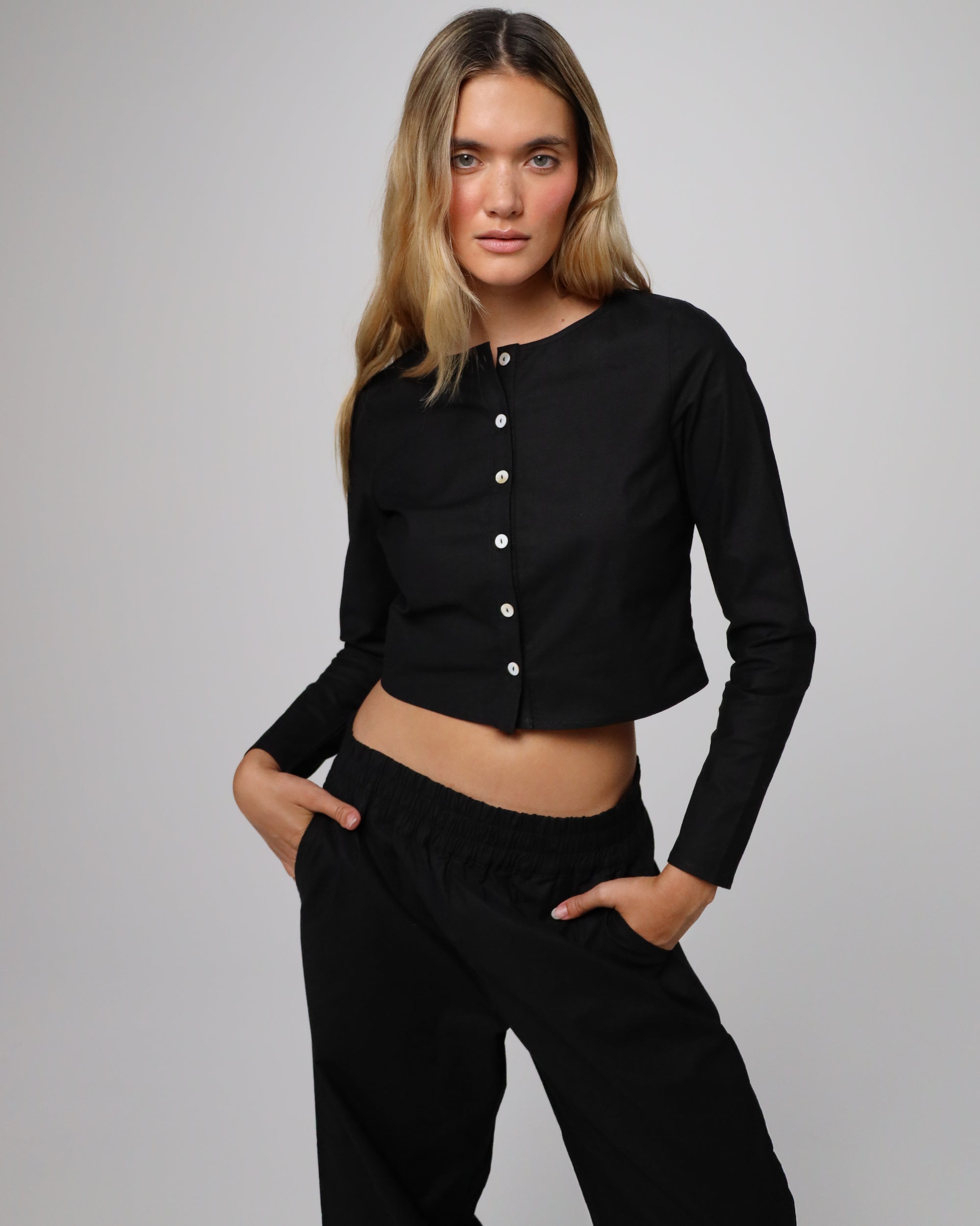 Full-body view of Aella Long Sleeve Woven Top (black) paired with Aella Mid Rise Relaxed Pants for a matching set.