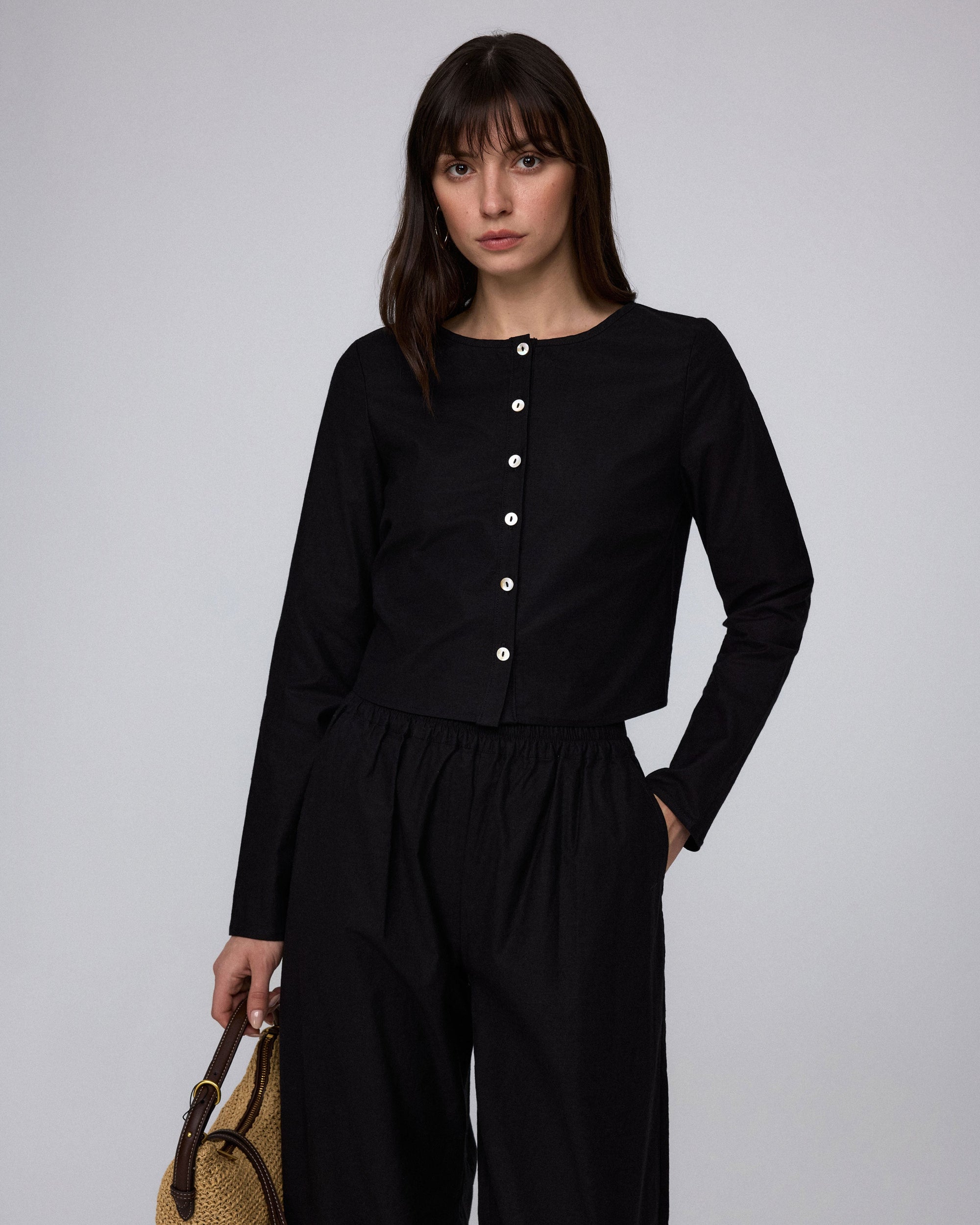 Side view of Aella Long Sleeve Woven Top (black) paired with Aella Mid Rise Relaxed Pants for a matching set.