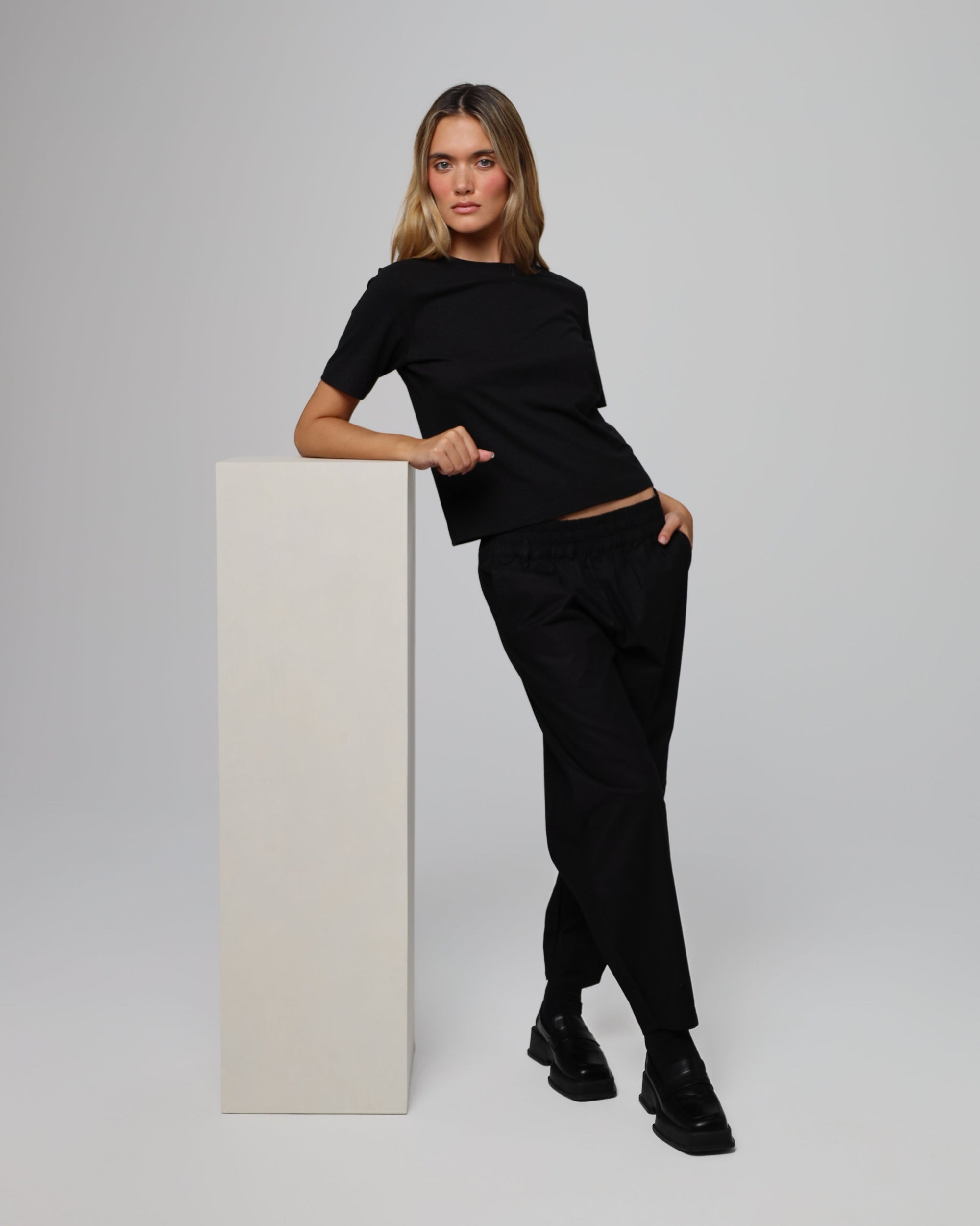 Model styling Aella Mid Rise Relaxed Tapered Pants (black) with the Hemp Essential Short Sleeve Tee for a coordinated look.