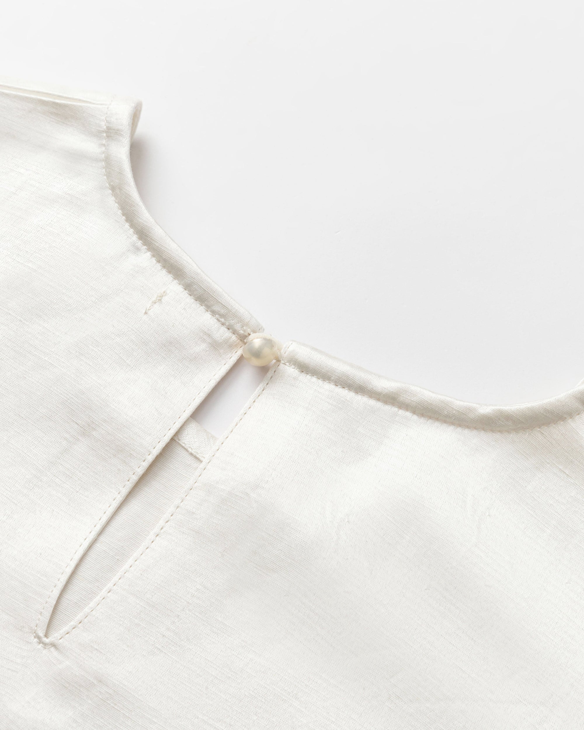 Detail shot of neckline, raglan seam, and hem finishing on Aven Raglan Dress (pearl white), highlighting refined construction.