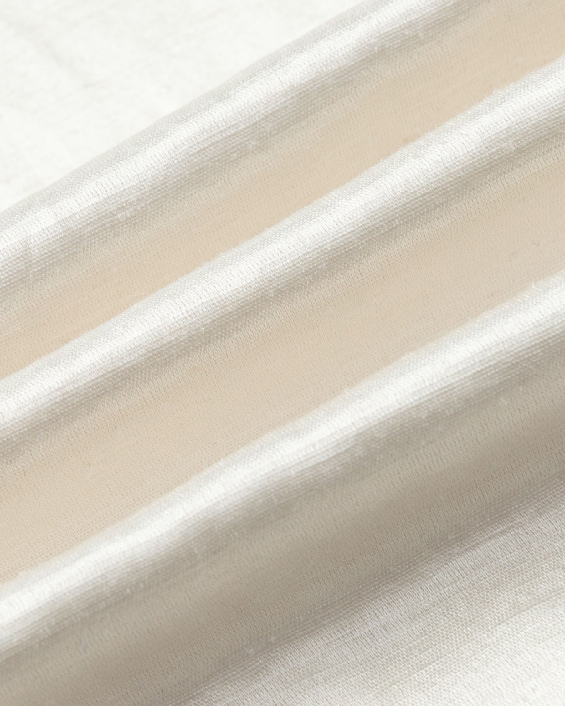 Textile close-up of Aven Raglan Dress (pearl white), highlighting natural fiber weave and luminous finish.