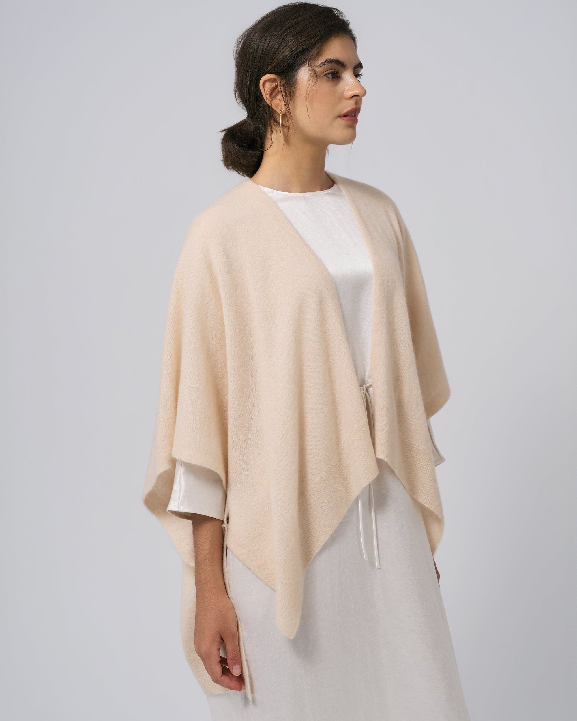 Detail of neckline and edge finish on almond milk wool–cashmere–hemp cape; refined trim and drape.