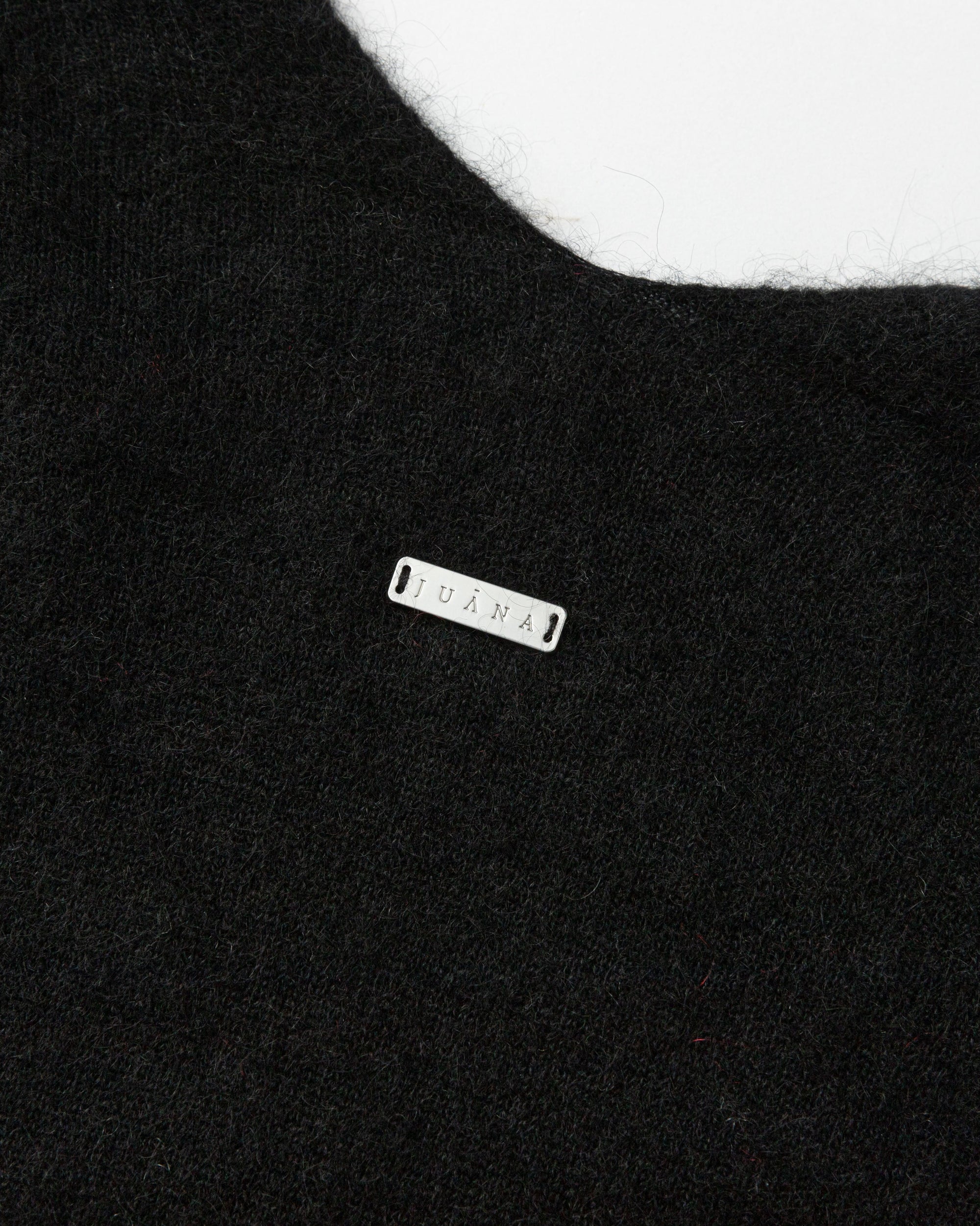 Detail of neckline and edge finish on black wool–cashmere–hemp cape; refined trim and drape.