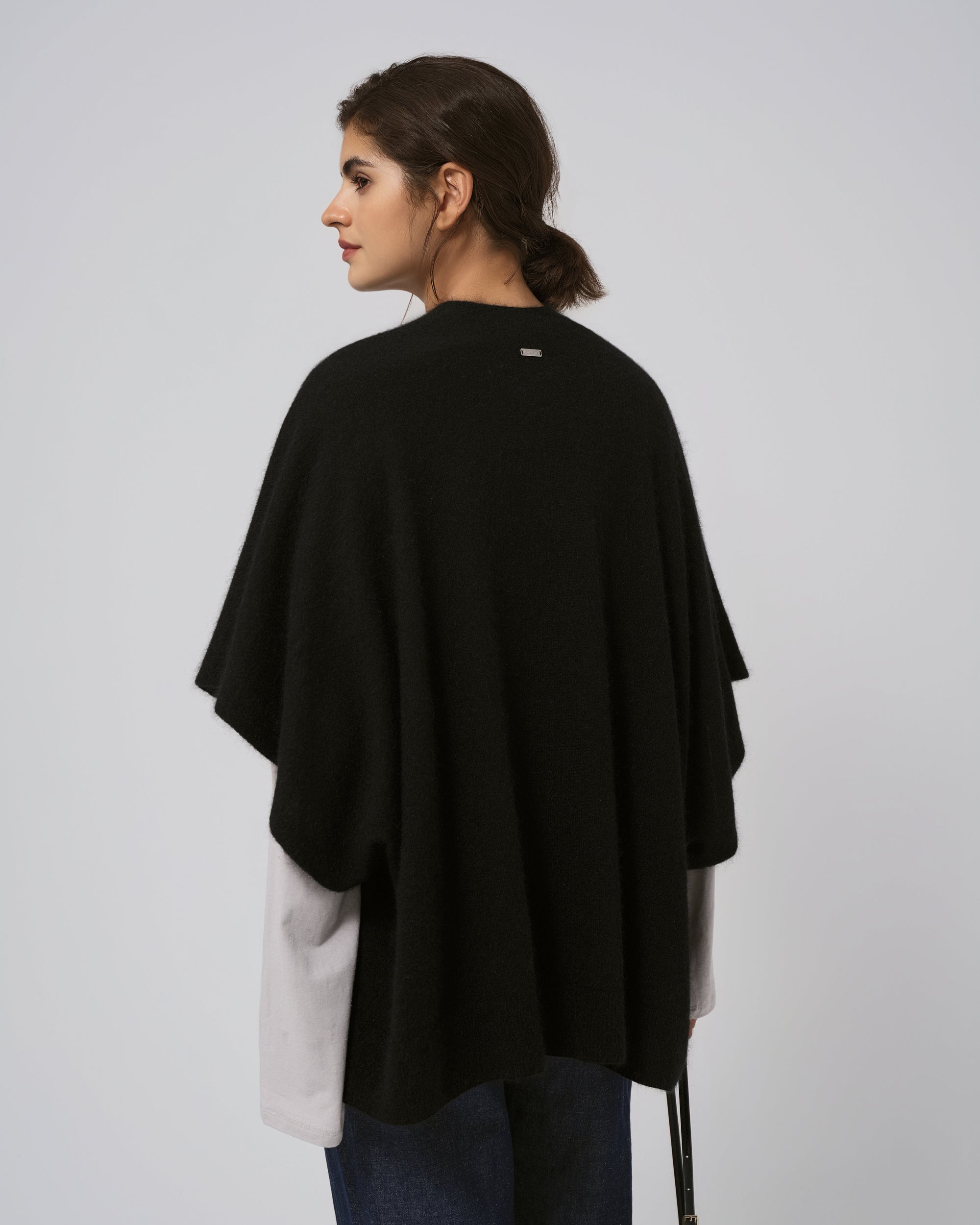 Model back view of black cape; smooth back panel and flowing hem.