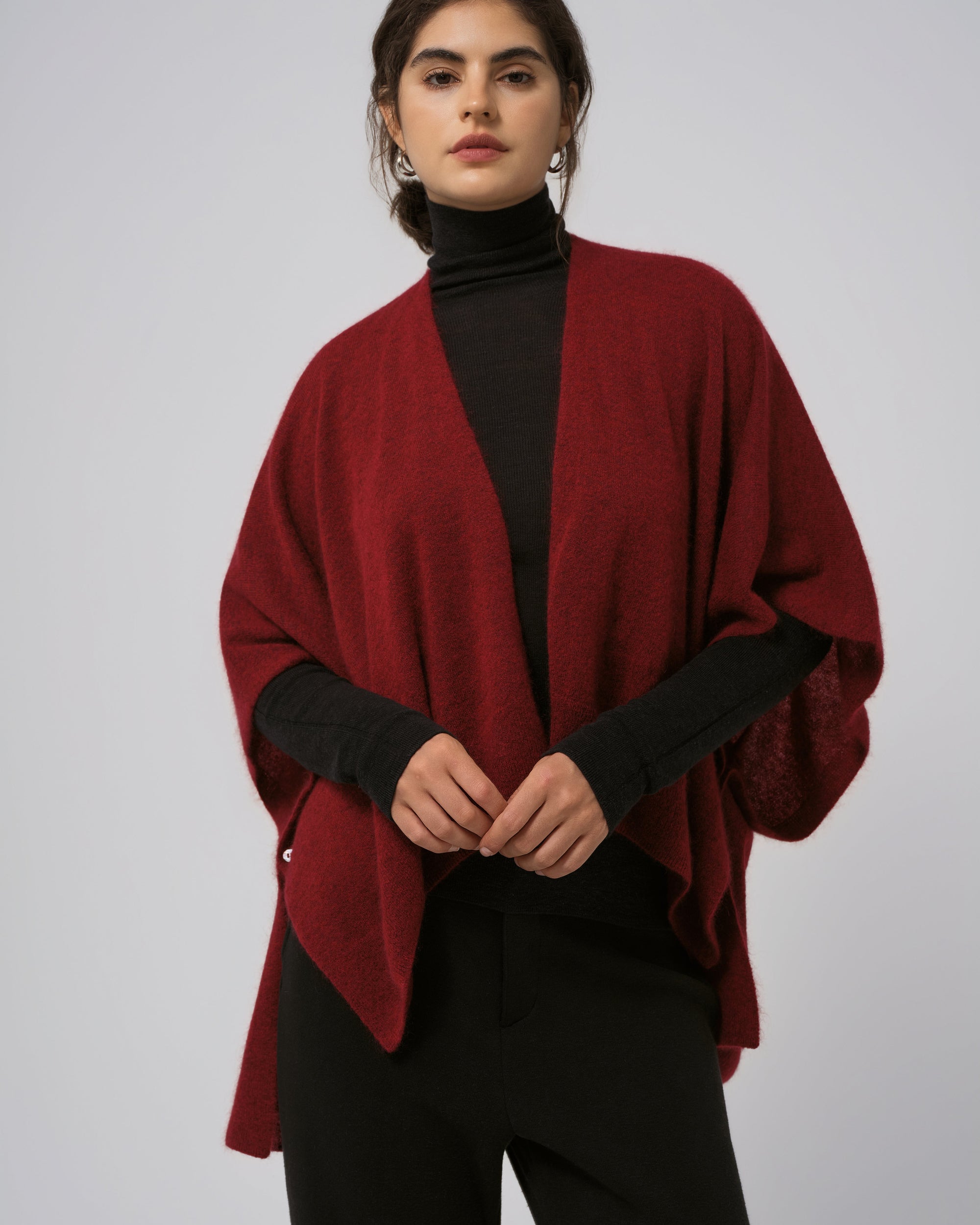 Model wearing Juana Cashmere Cape in burgundy (wool–cashmere–hemp knit), showing warm hue and elegant drape.