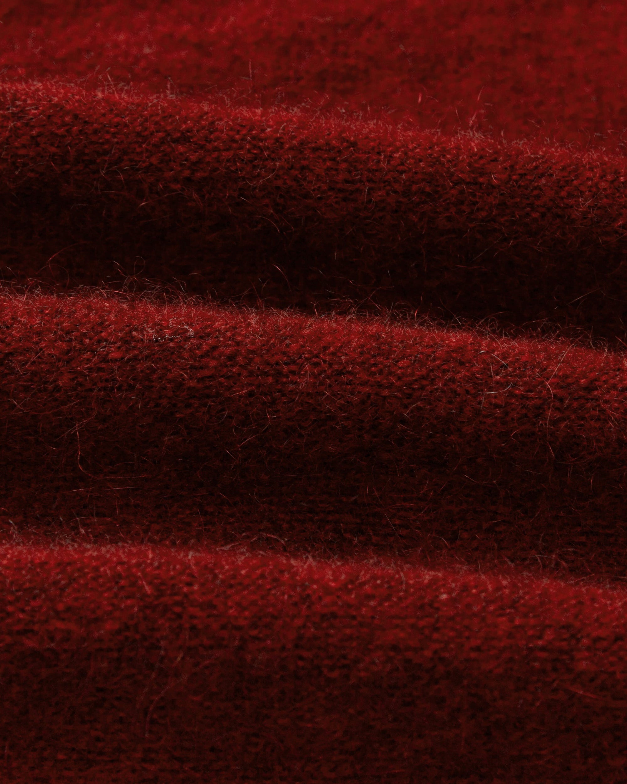Textile close-up of burgundy wool–cashmere–hemp knit; fine, soft texture.