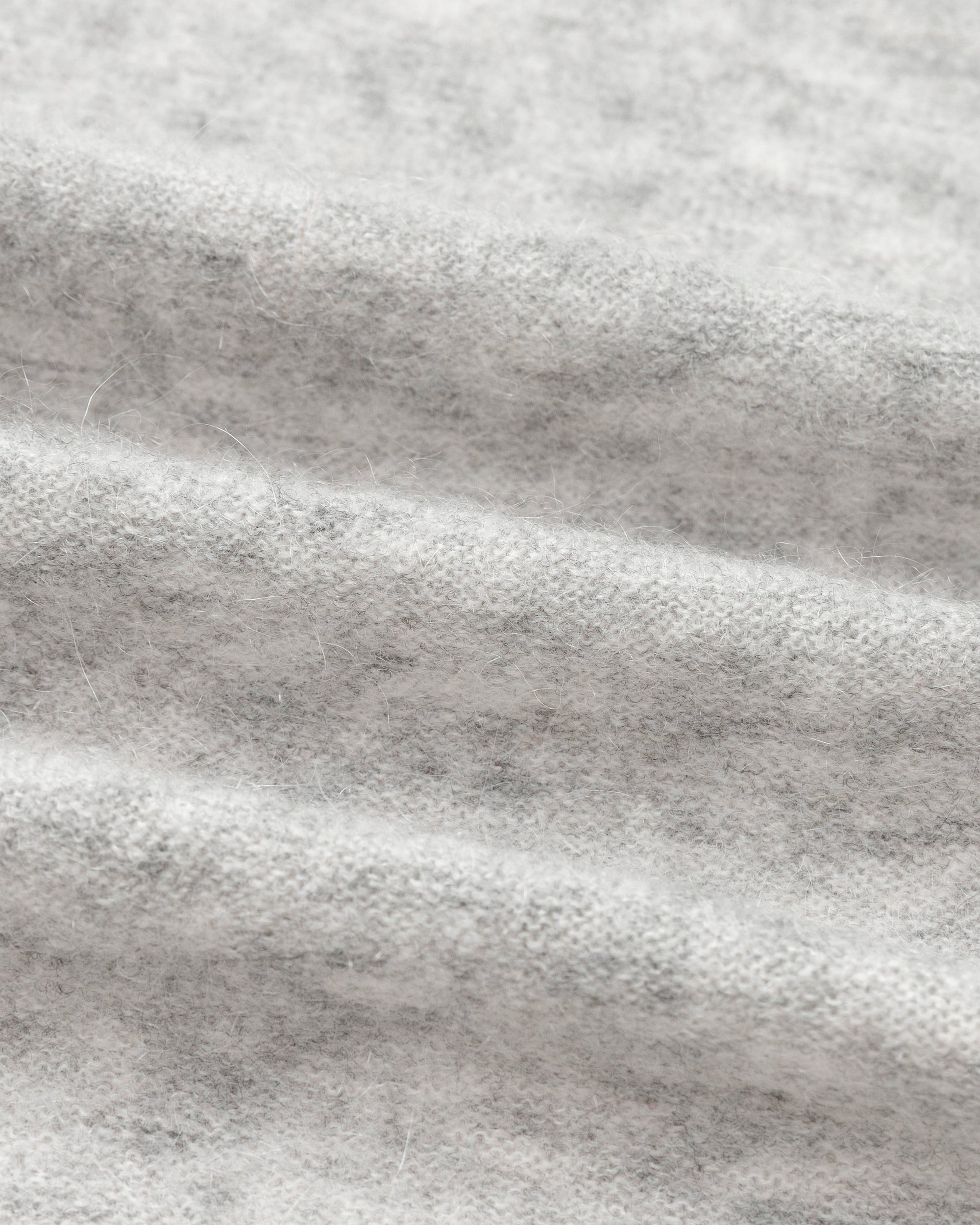Textile close-up of light grey wool–cashmere–hemp knit; fine gauge and soft handfeel.