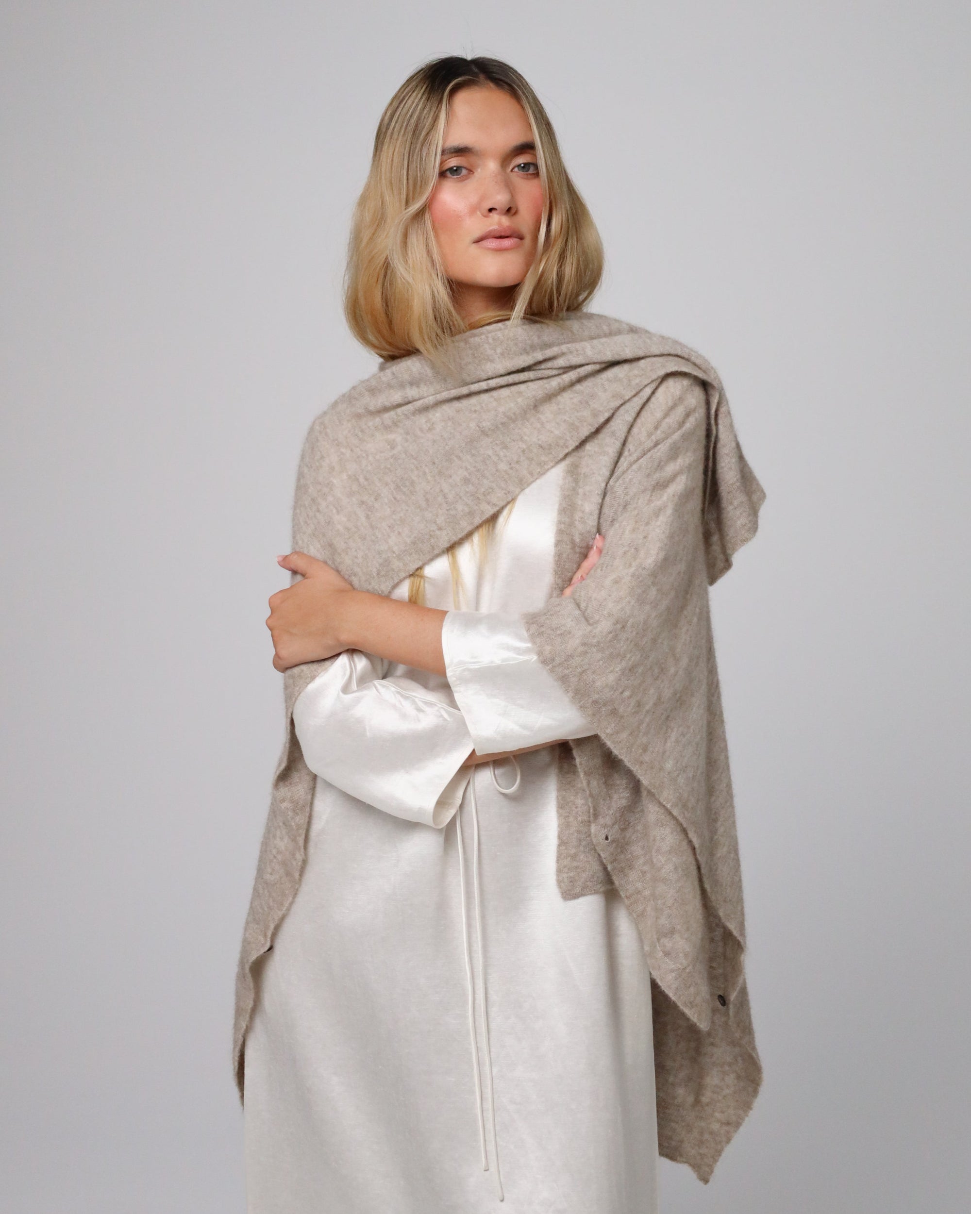 Woman wearing Juana Cashmere Cape in oatmeal wool–cashmere–hemp knit, showing fluid, sculptural drape.