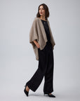 Woman wearing Juana Cashmere Cape in oatmeal wool–cashmere–hemp knit, showing fluid, sculptural drape.