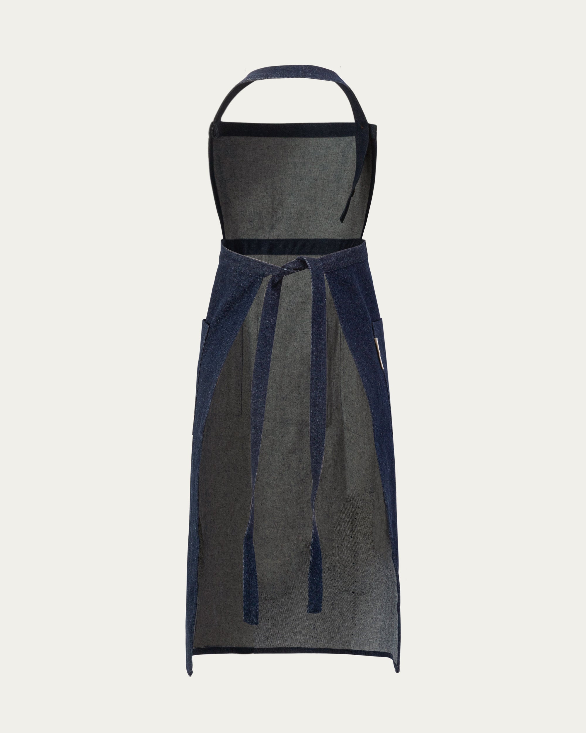 Denim Atelier Functional Apron (indigo) on ghost mannequin, back view showing adjustable strap configuration.
