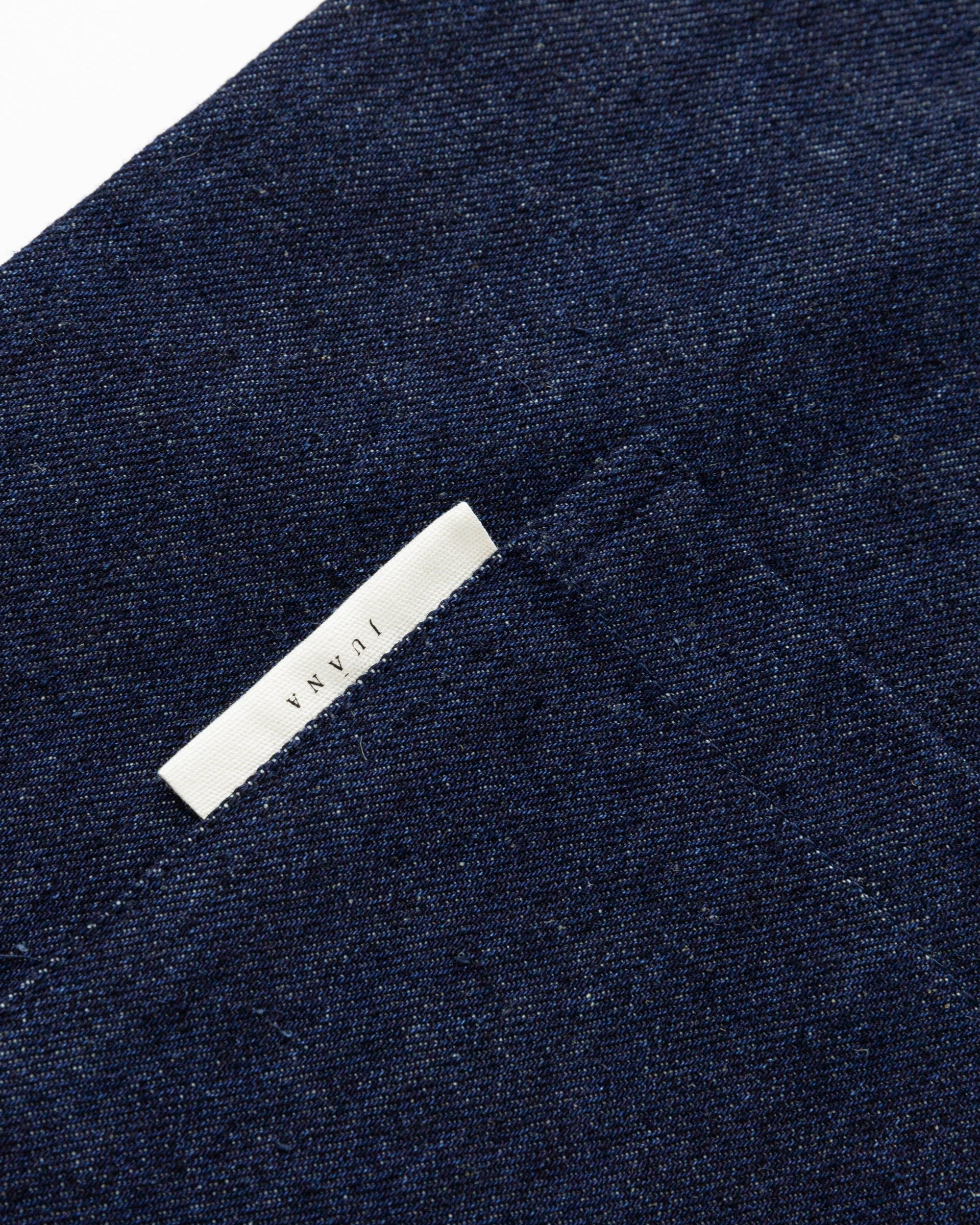 Detail shot of adjustable buttoned straps and reinforced pocket stitching on Denim Atelier Functional Apron (indigo).