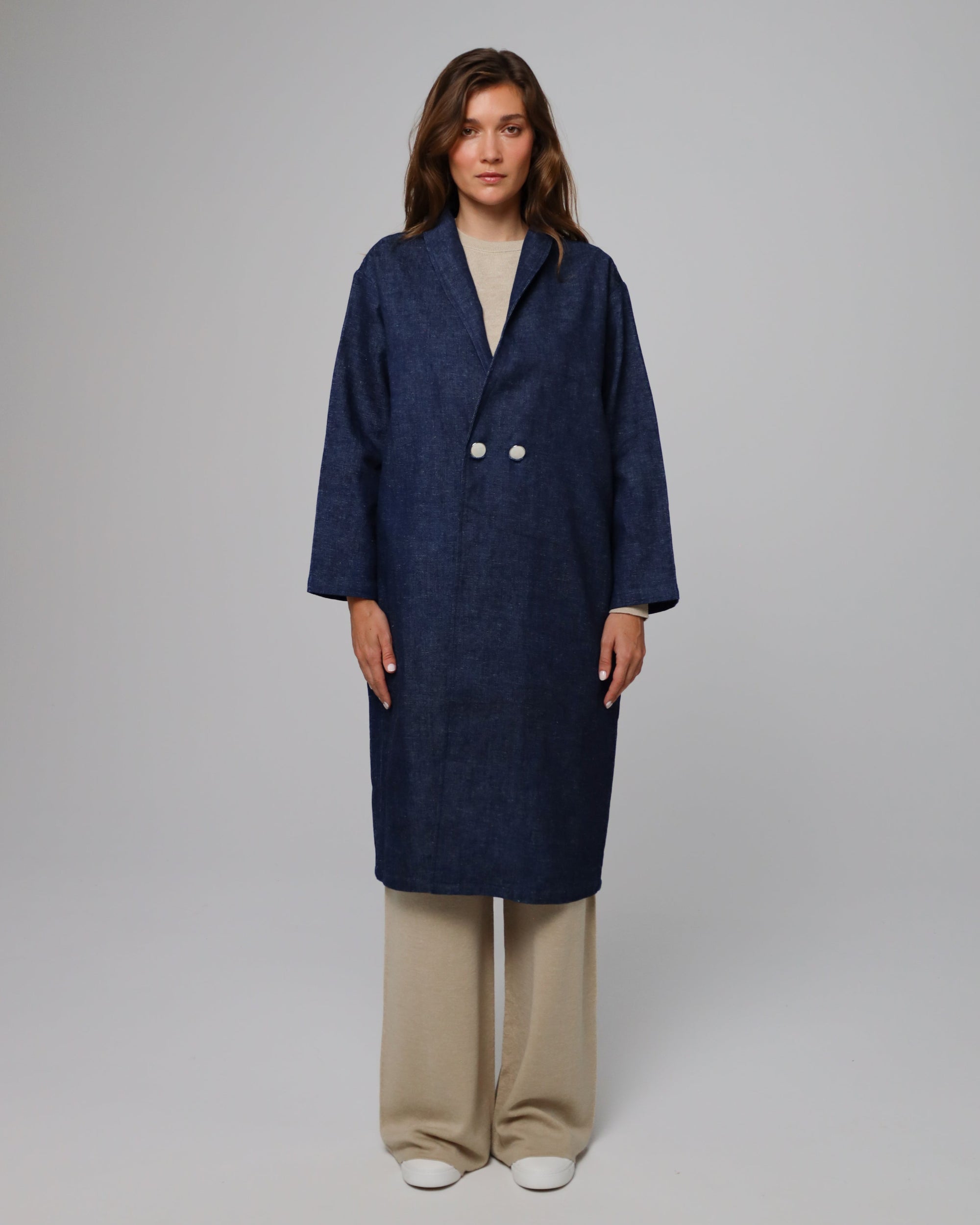 Model wearing Juana Denim Atelier Trench Coat in indigo denim (hemp–organic cotton), showing elongated trench silhouette.