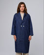 Model wearing Juana Denim Atelier Trench Coat in indigo denim (hemp–organic cotton), showing elongated trench silhouette.
