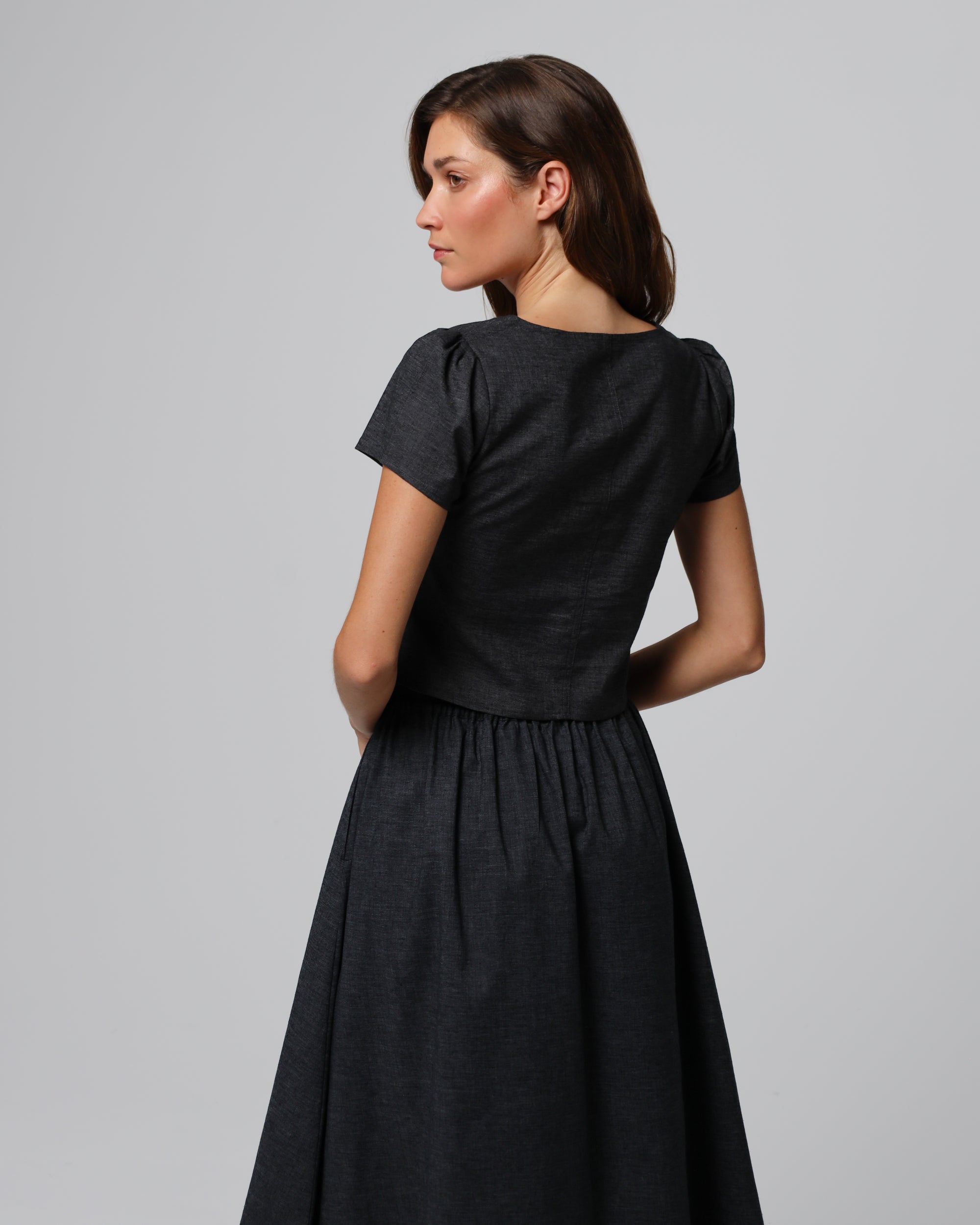 Model styling the Button Front Top (washed black) with tailored skirt for minimalist polish.