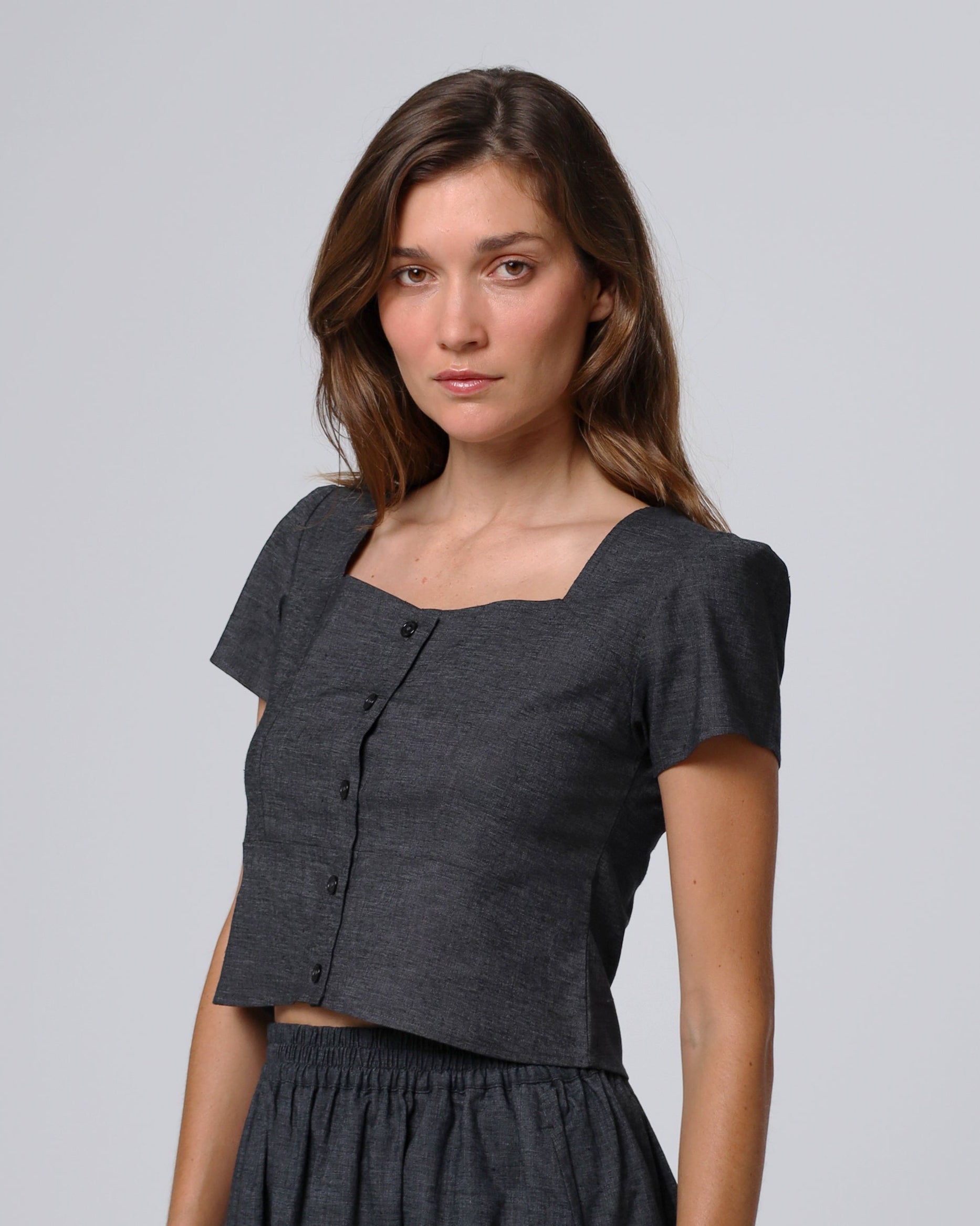 Woman wearing Juana Hemp Blend Button Front Top in washed black hemp–recycled stretch twill, showing clean neckline and sculpted fit.