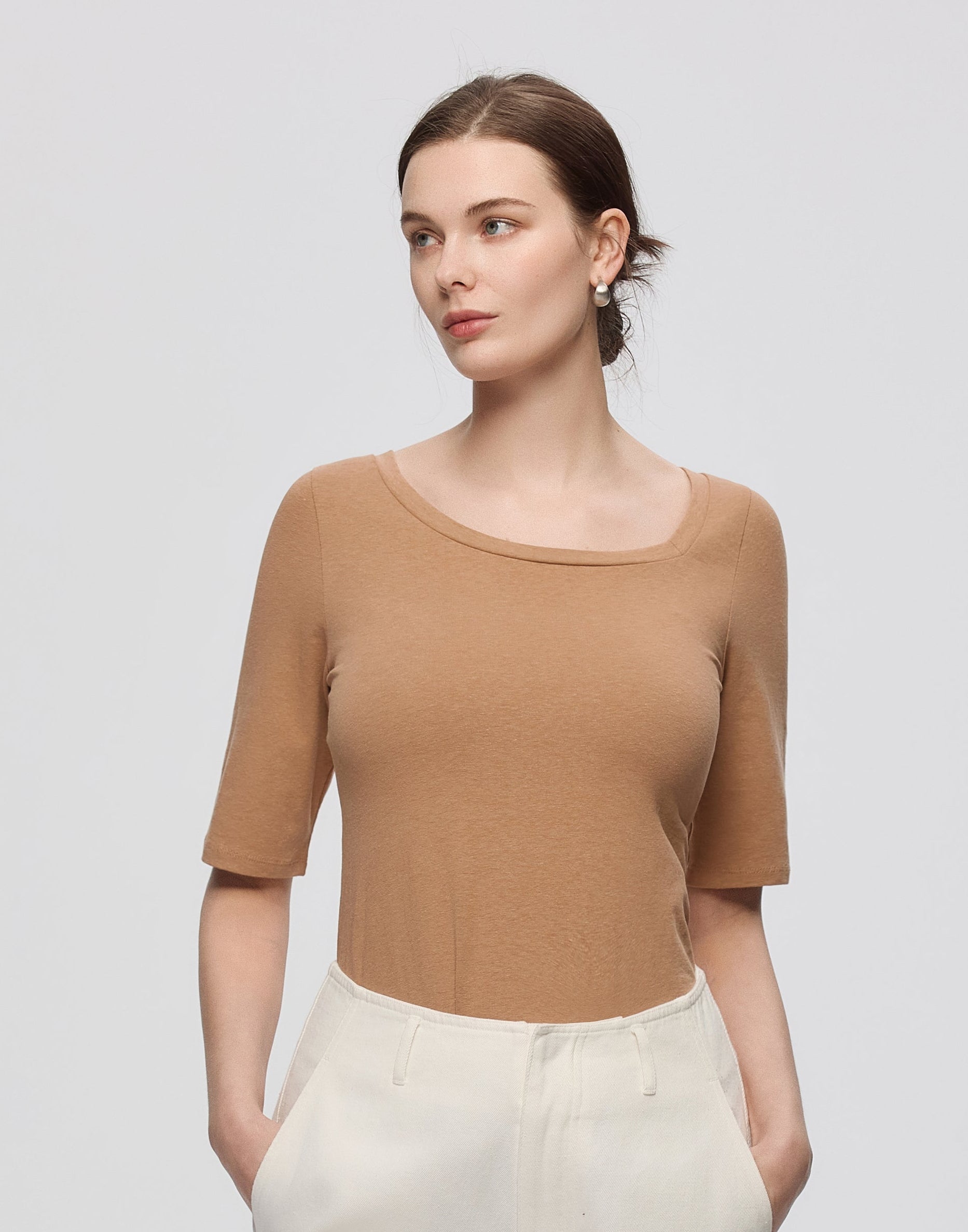 Woman wearing Juana Hemp Essentials Asymmetrical Neckline Tee in fawn hemp–organic cotton stretch blend, styled for sustainable everyday wear.