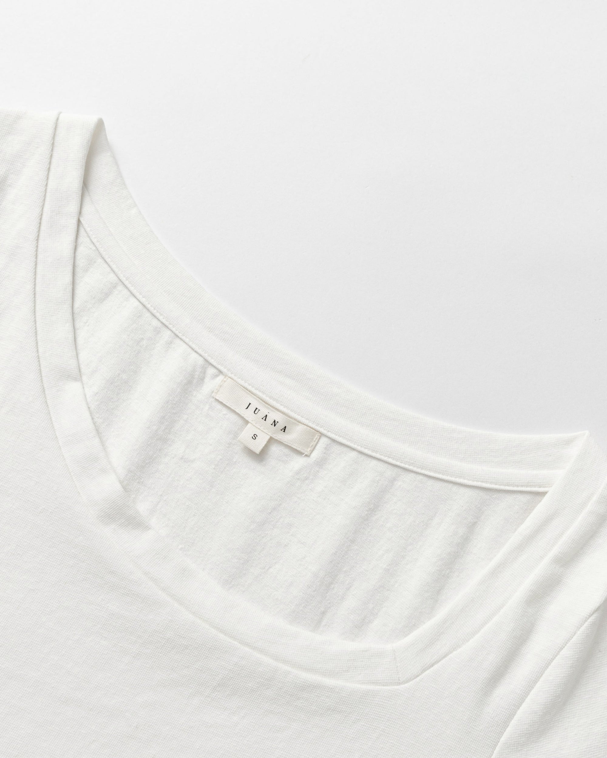 Detail shot of the asymmetrical neckline and seam finish on Asymmetrical Neckline Tee (white).