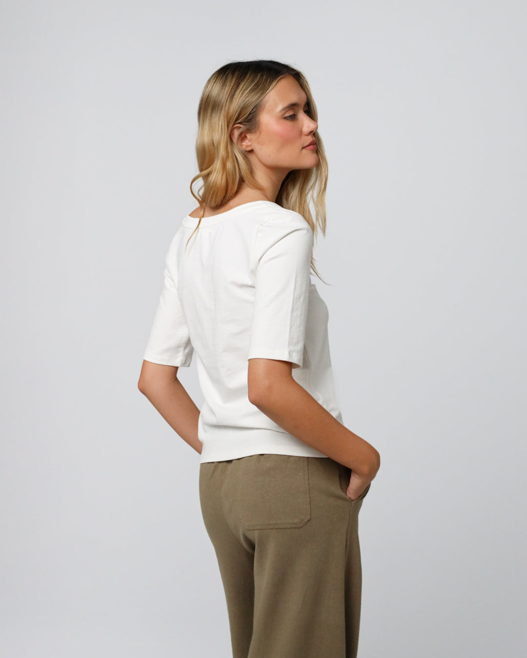 Model styling Asymmetrical Neckline Tee (white) with tailored trousers for minimalist polish.