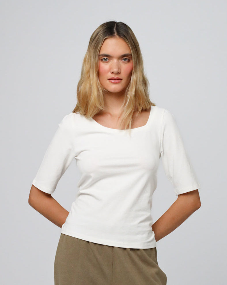 Woman wearing Juana Hemp Essentials Asymmetrical Neckline Tee in white hemp–organic cotton stretch blend, styled for sustainable everyday wear.