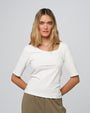 Woman wearing Juana Hemp Essentials Asymmetrical Neckline Tee in white hemp–organic cotton stretch blend, styled for sustainable everyday wear.