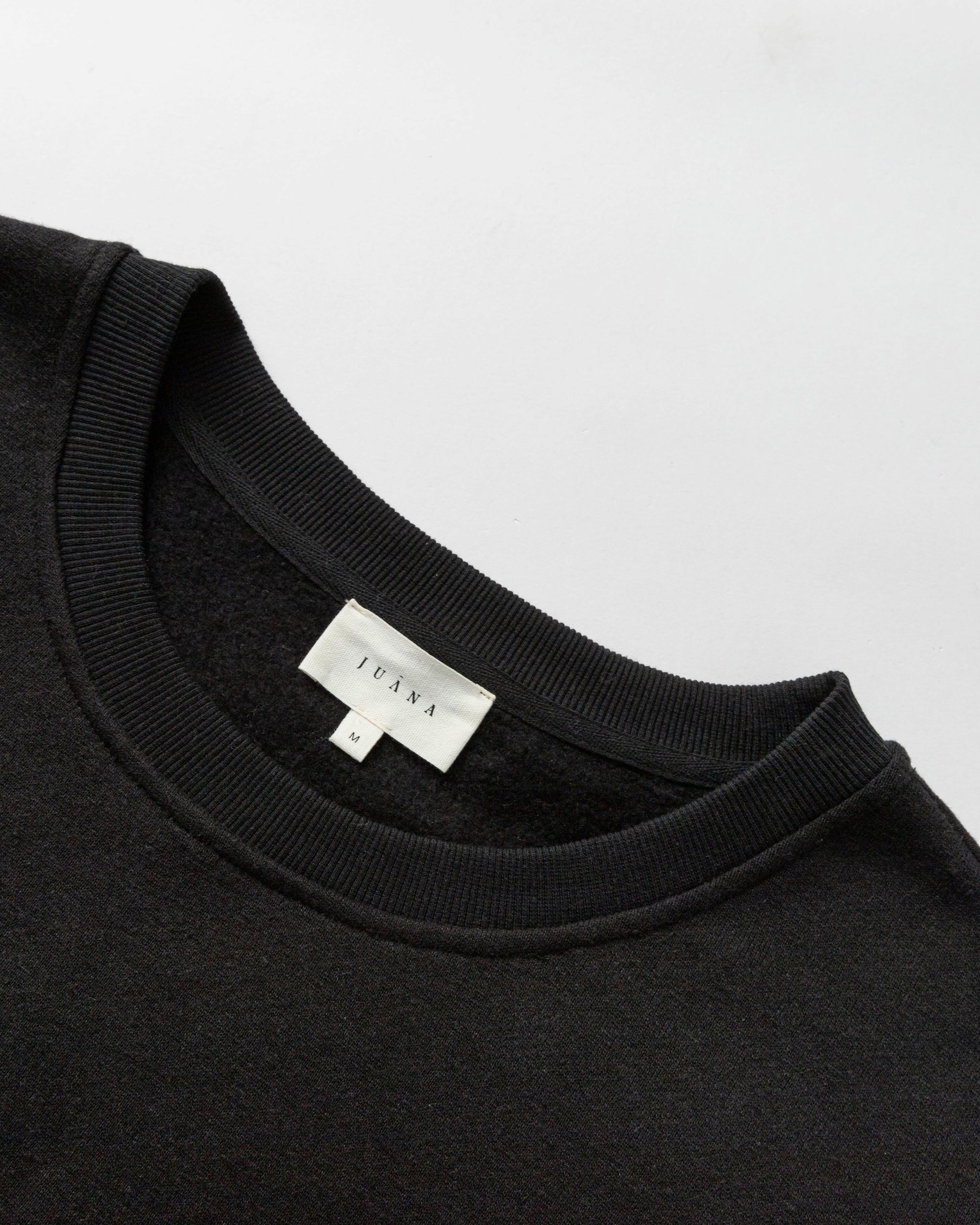 Detail shot of neckline, hem, and fleece interior on Fleece Cropped Sweater (black).