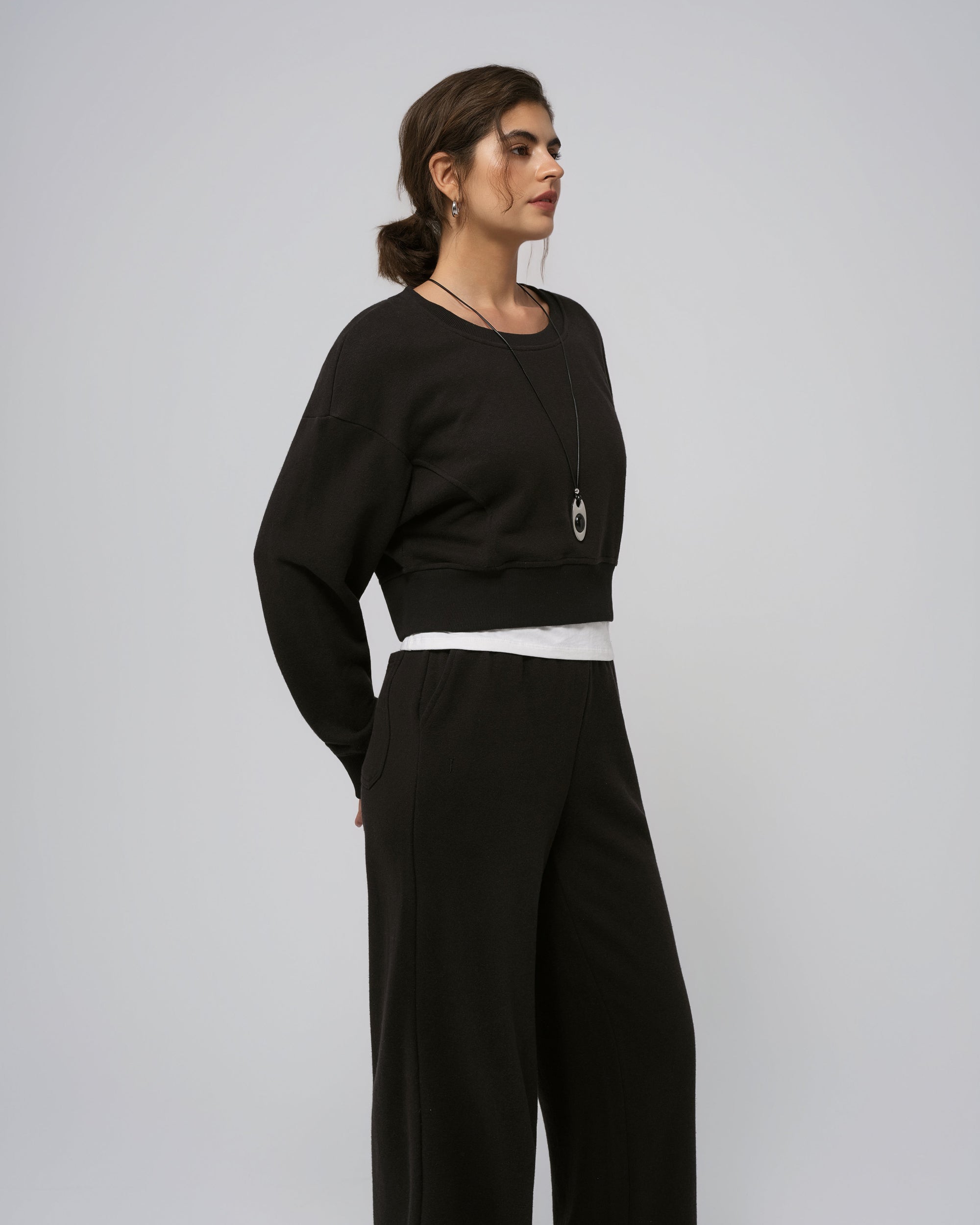 Side view of black cropped sweater; cropped length and relaxed shoulder.