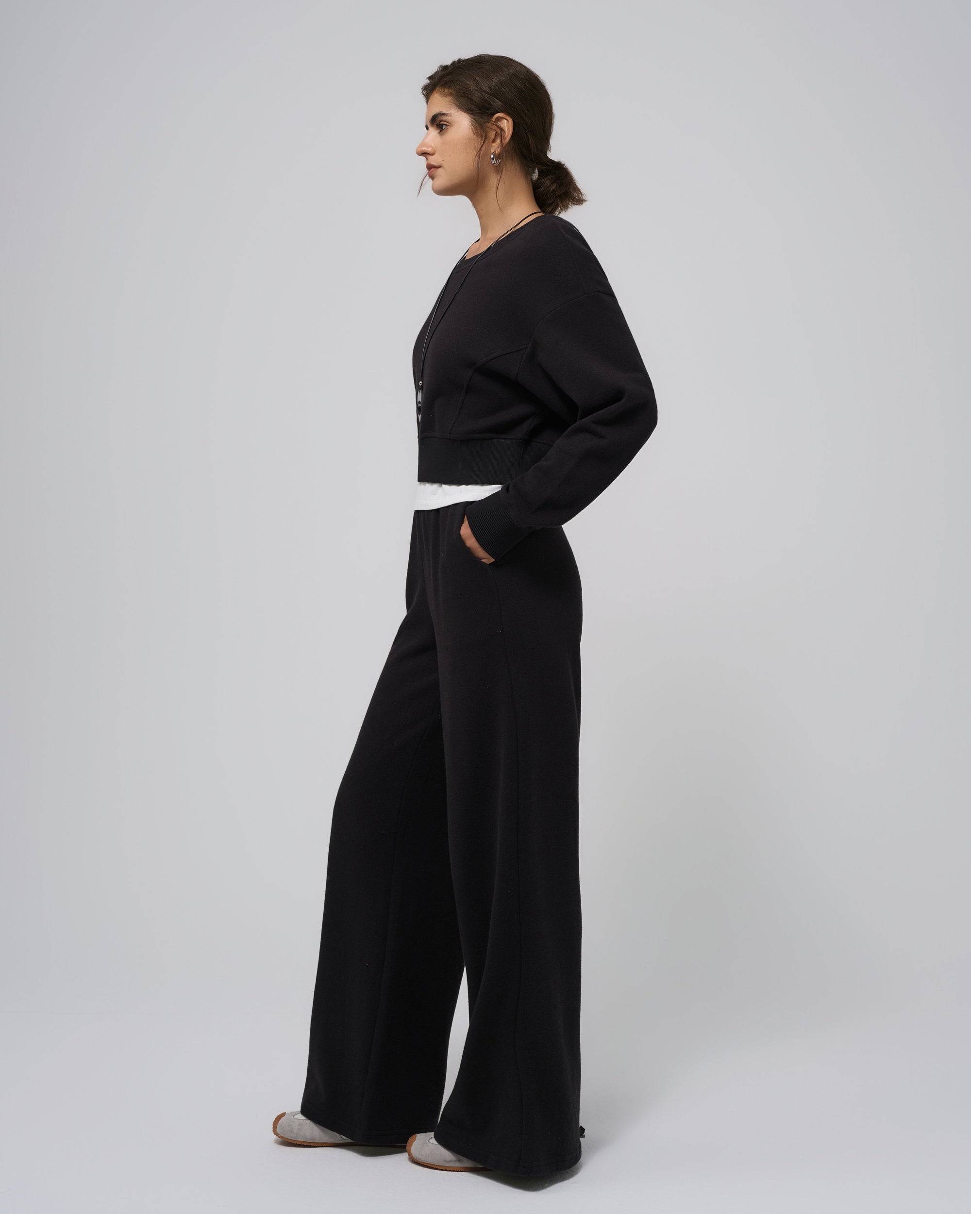 Side view of black fleece sweatpants; mid‑rise waist and taper.
