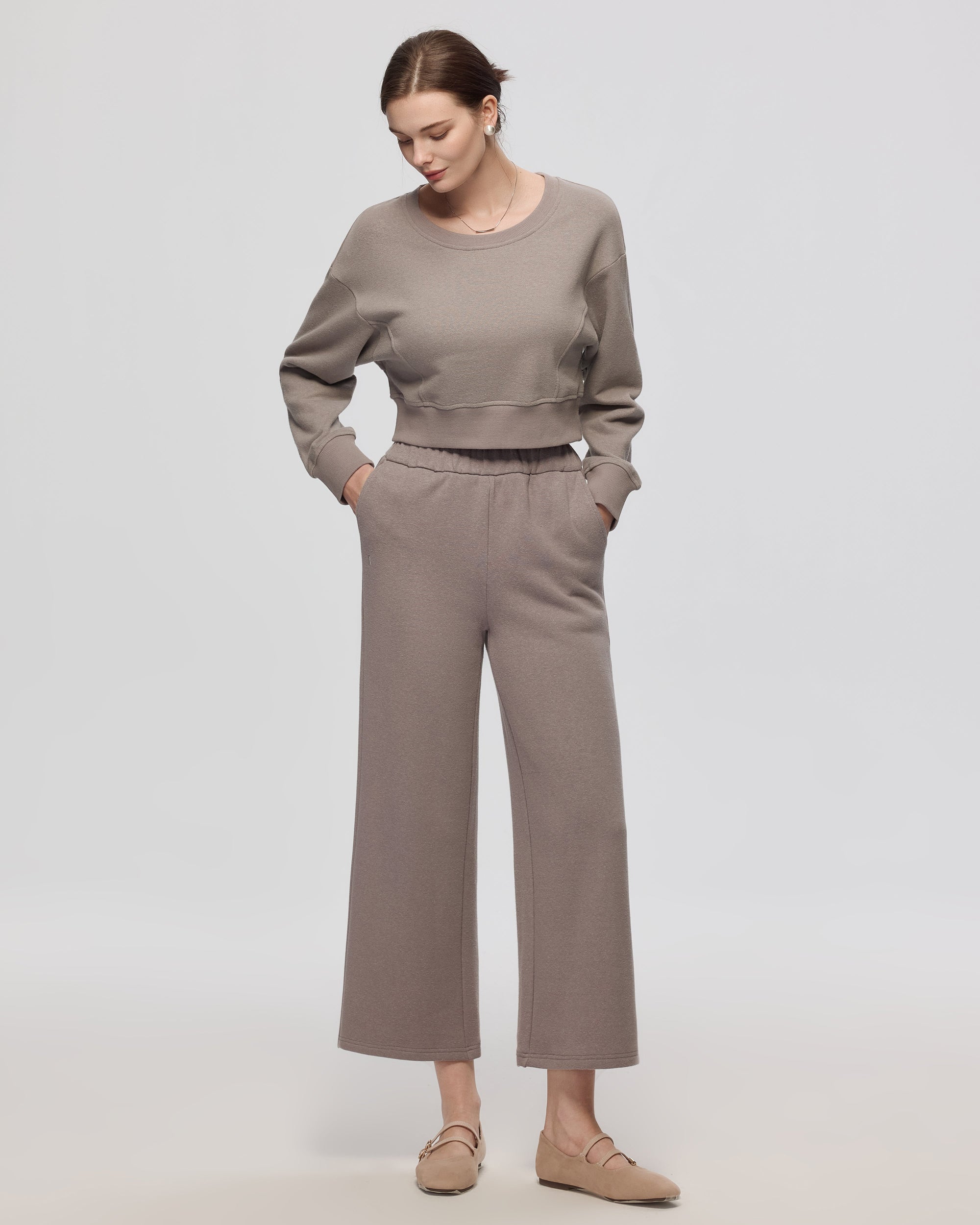 Model wearing coordinated gray fleece set (cropped sweater + sweatpants);7/8 length, front view.