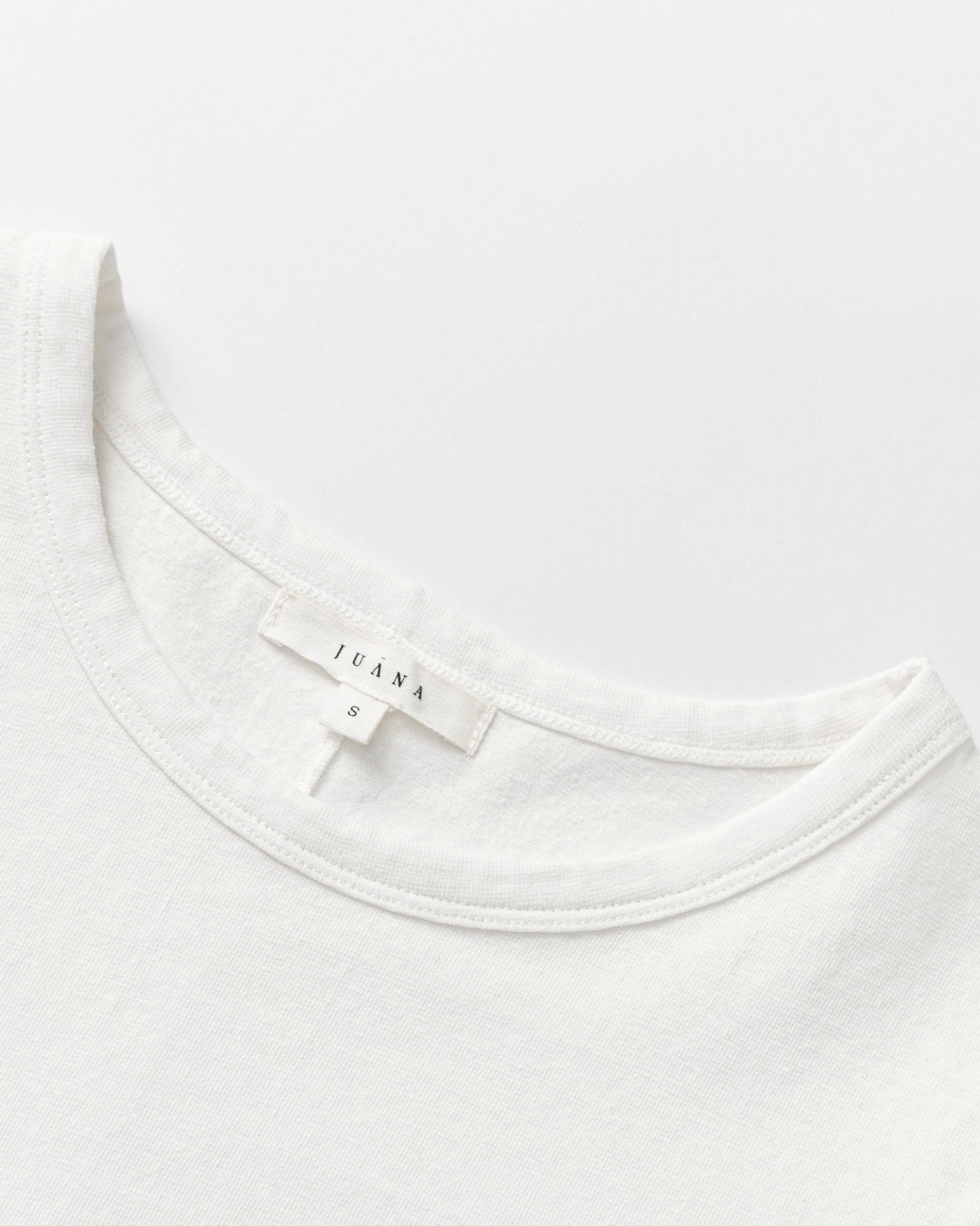 Detail shot of neckline, sleeve hem, and stitching on Long Sleeve Tee (white).