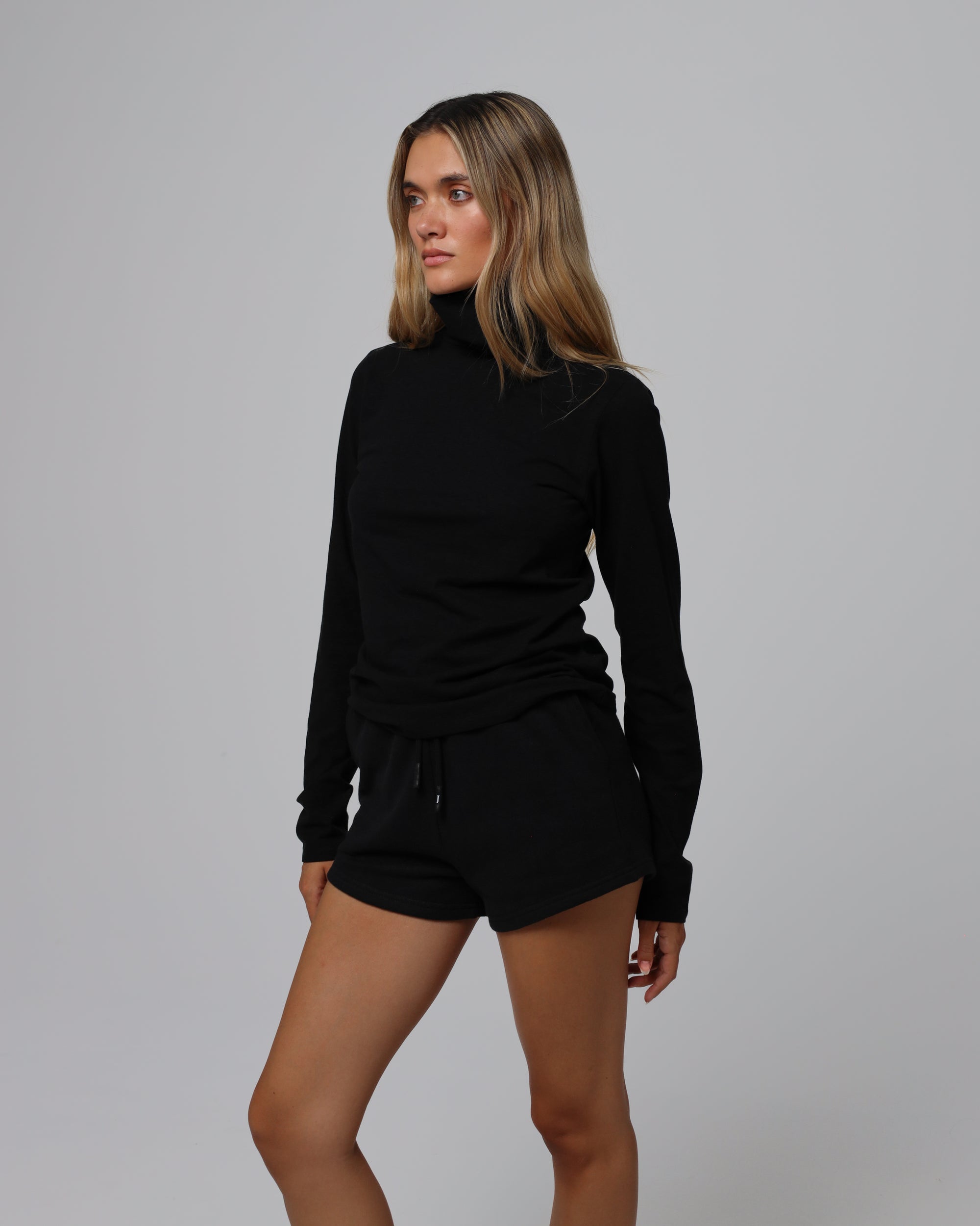 Woman wearing Juana Hemp Essentials Mockneck in black hemp–organic cotton stretch blend, styled for sustainable everyday wear.