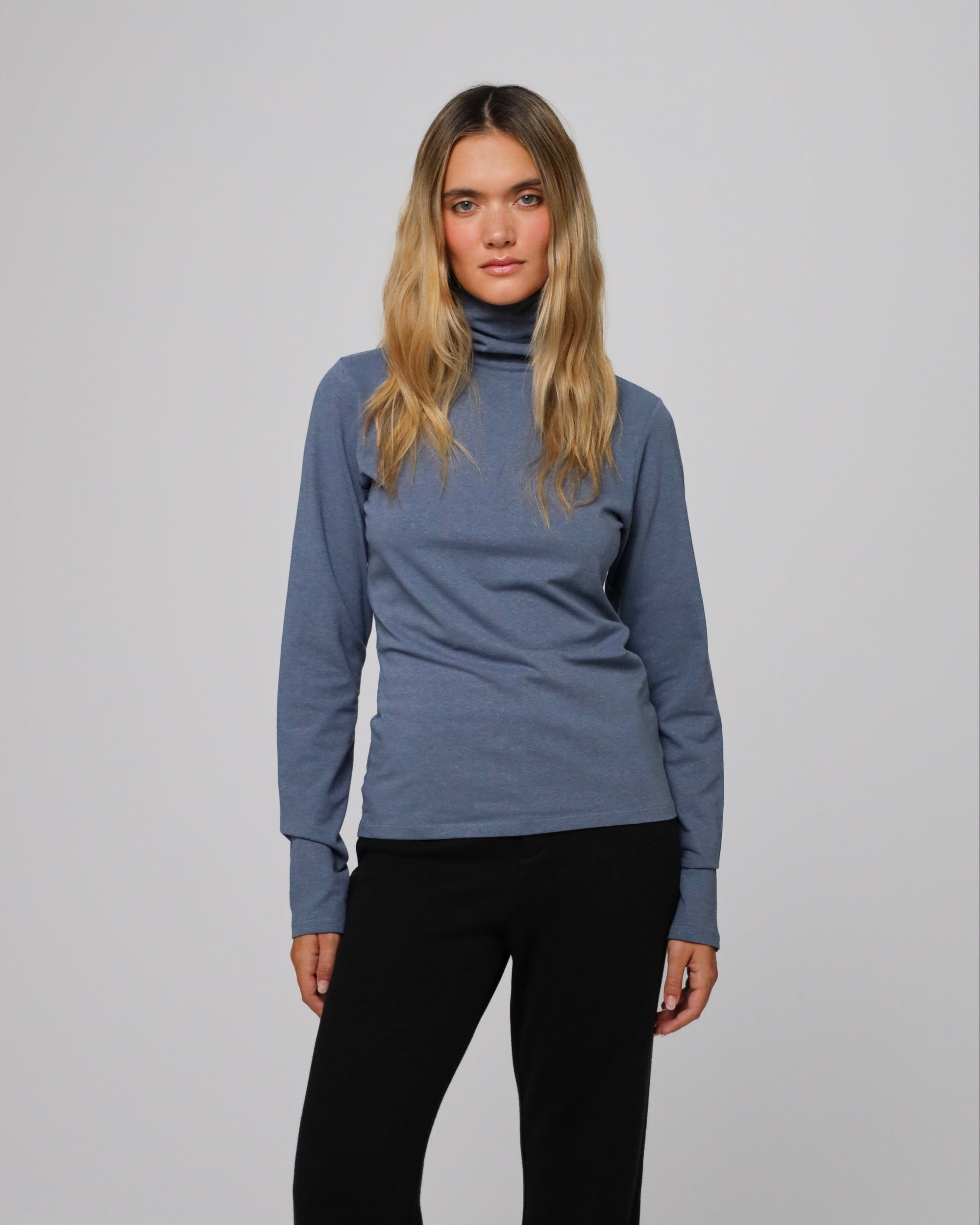 Model styling the Mockneck (blue) with tailored trousers for a sleek, minimalist look.