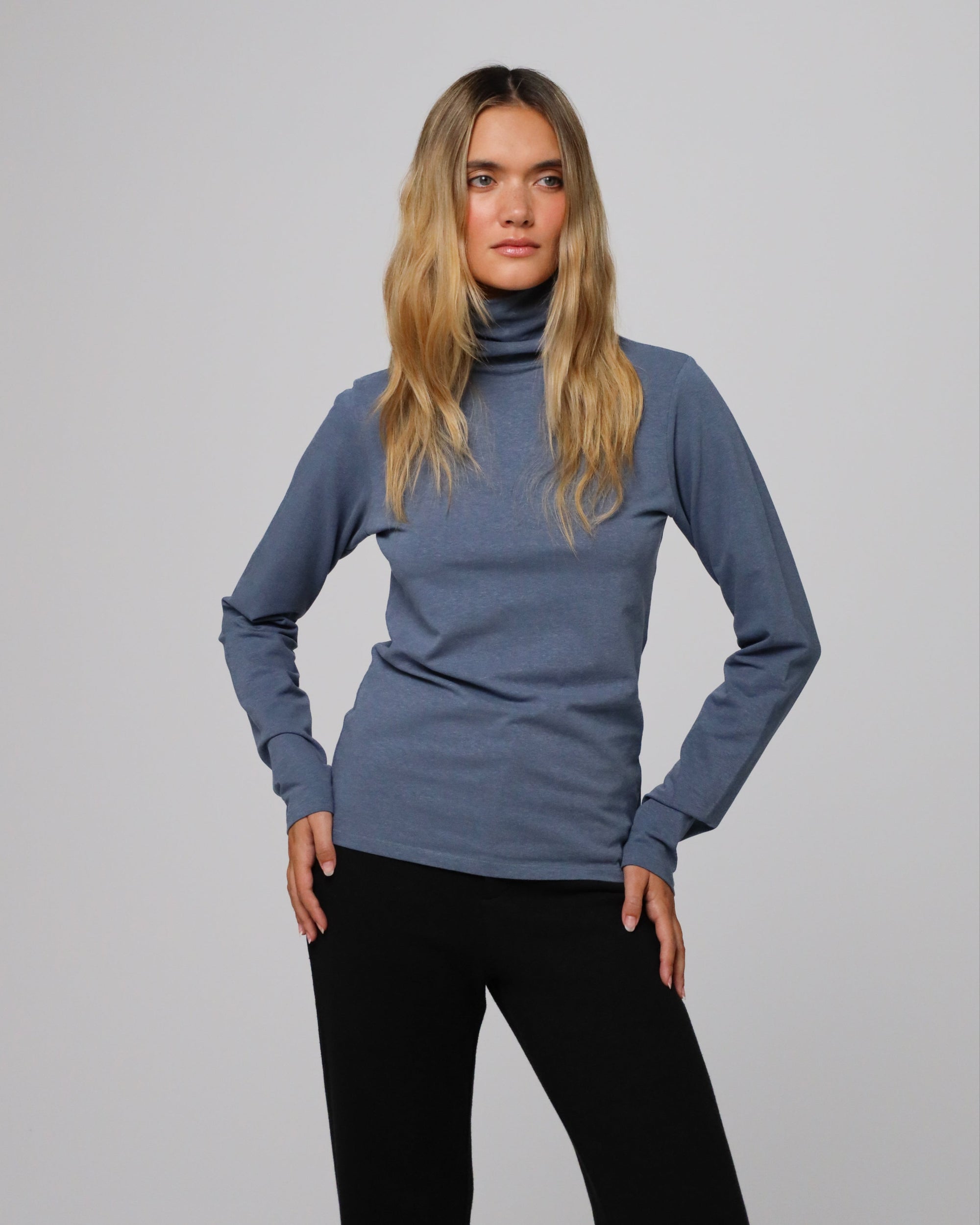 Woman wearing Juana Hemp Essentials Mockneck in blue hemp–organic cotton stretch blend, styled for sustainable everyday wear.