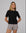 Model wearing Juana Hemp Essentials Short Sleeve Tee in black hemp–organic cotton stretch blend, styled for sustainable everyday wear.