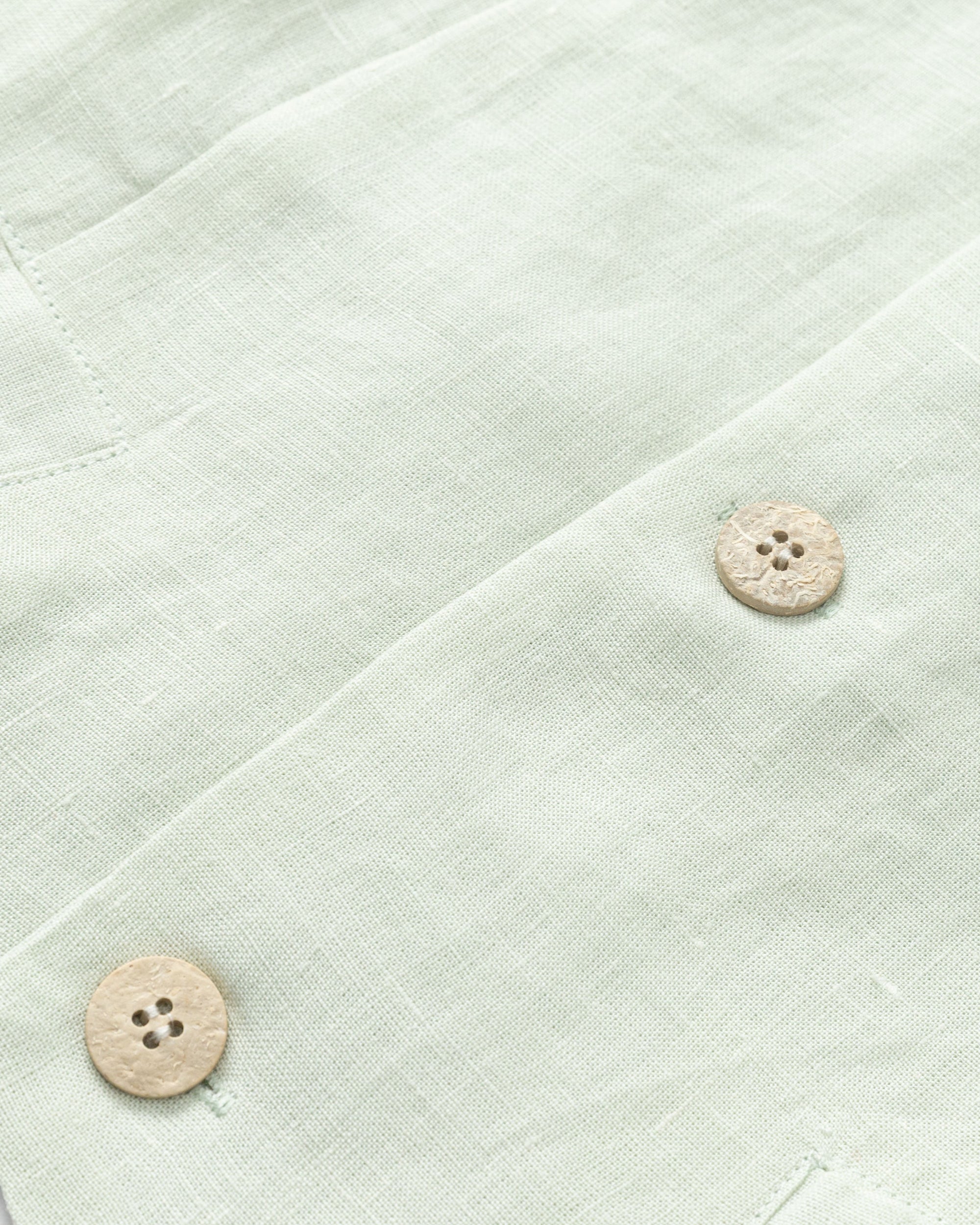 Flat-lay detail of Juana Hemp Tailored Vest in light mint (hemp), showing corozo buttons and neat stitching.