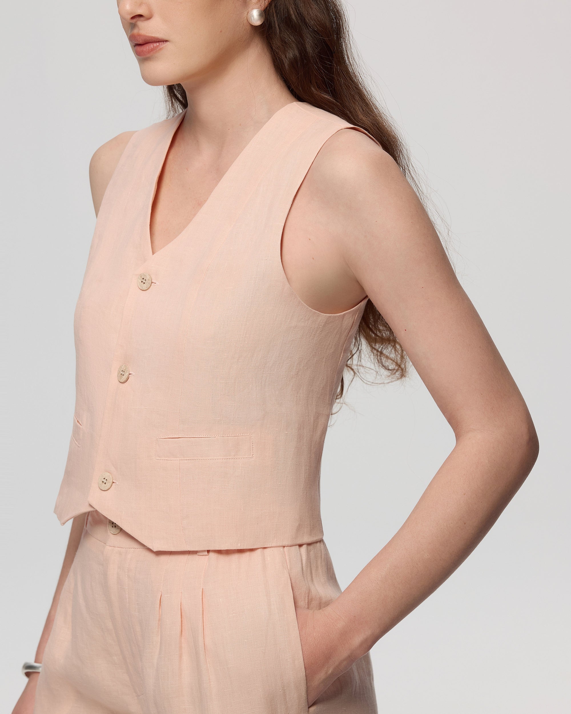 Model wearing Juana Hemp Tailored Vest in light peach (hemp), side view showing structured drape and length.