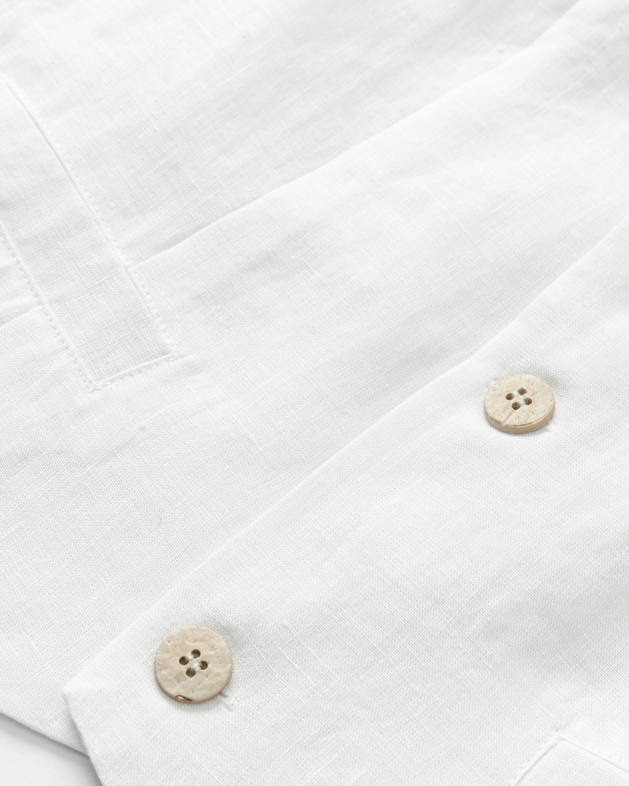 Flat-lay detail of Juana Hemp Tailored Vest in white (hemp), showing corozo buttons and neat stitching.