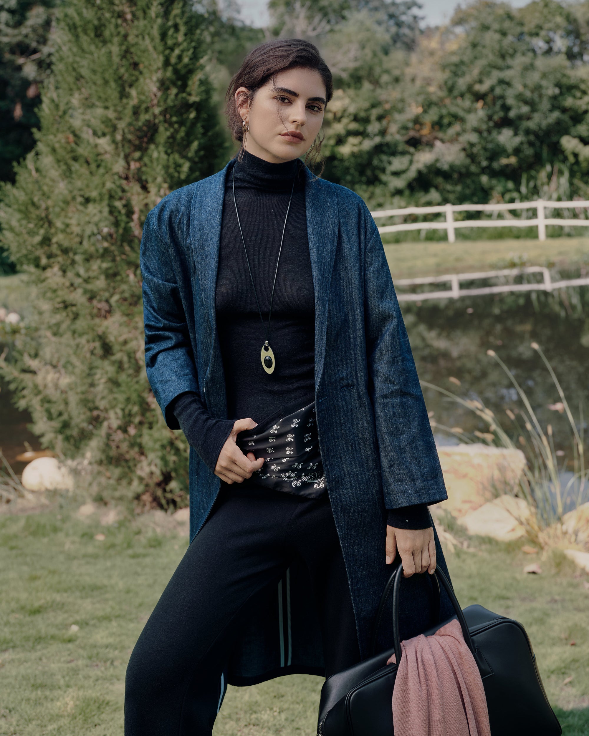 Lakeside back view showing longline blue denim trench layered over black Ossa turtleneck and black classic high rise pants; smooth movement and structure.