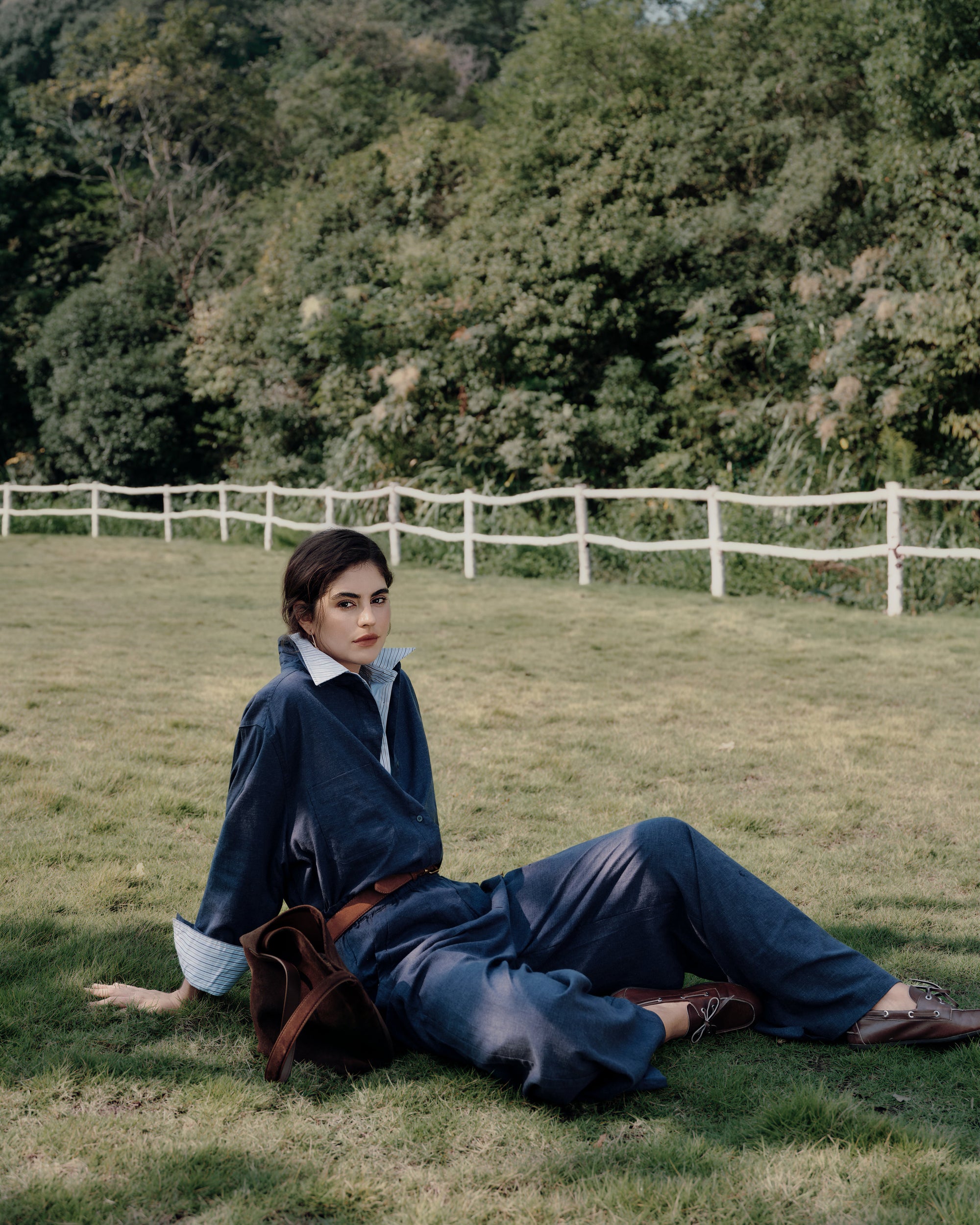 Garden seated portrait wearing Lyricist Oversized Shirt indigo blue over white shirt with Lyricist Pull-on Pants indigo blue; airy, breathable twill.