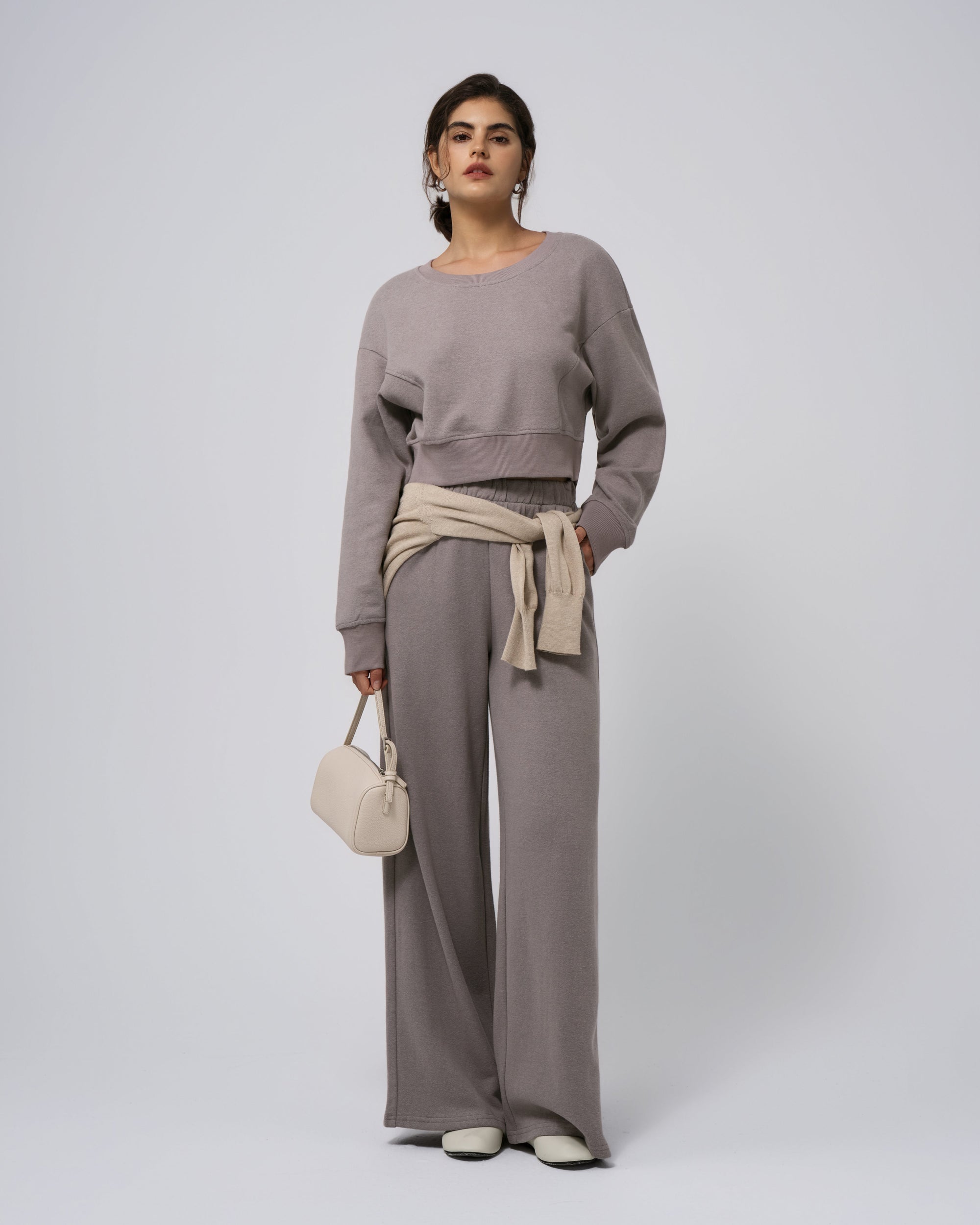 Model wearing coordinated gray fleece set (cropped sweater + sweatpants); front view.