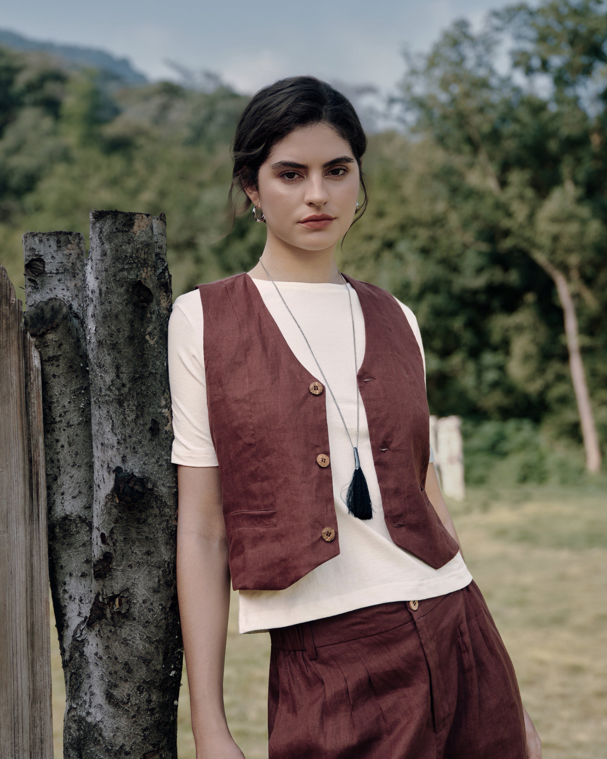 Model wearing Juana Hemp Essentials Short Sleeve Tee (white, hemp–organic cotton blend) layered with Juana Hemp Tailored Vest (expresso, 100% hemp with corozo buttons), styled for sustainable everyday wear.