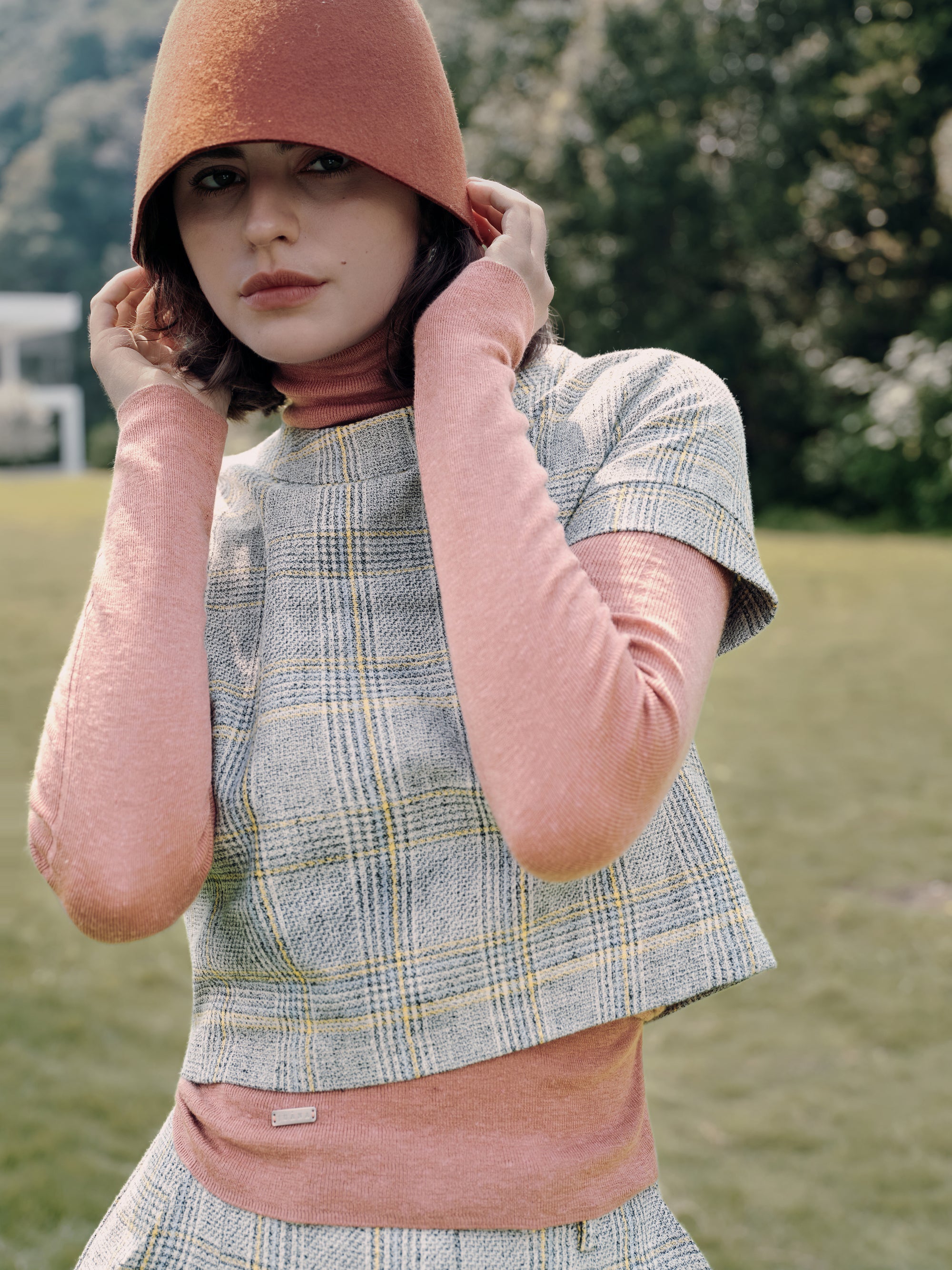 Model wearing Juana Ossa Knitted Hemp Turtleneck (Mocha Mousse, merino–silk–hemp knit) layered with Plaid Theory Top (yellow–grey plaid, hemp–organic cotton blend), styled for elevated everyday wear.