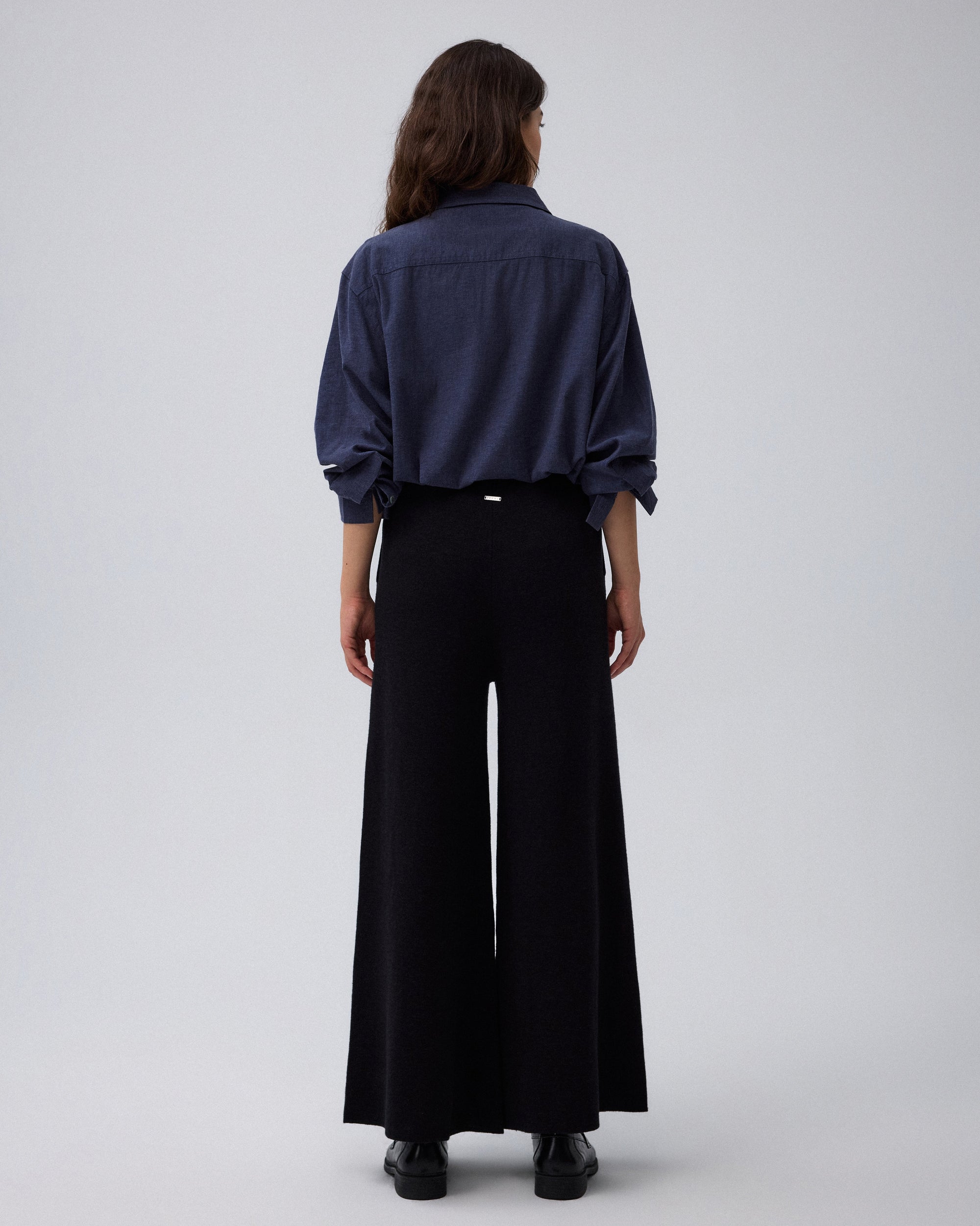 Juana Mid-Rise Cropped Pants in Black (merino wool–hemp–silk) shown on a model from the back with a clean sweater-knit drape.