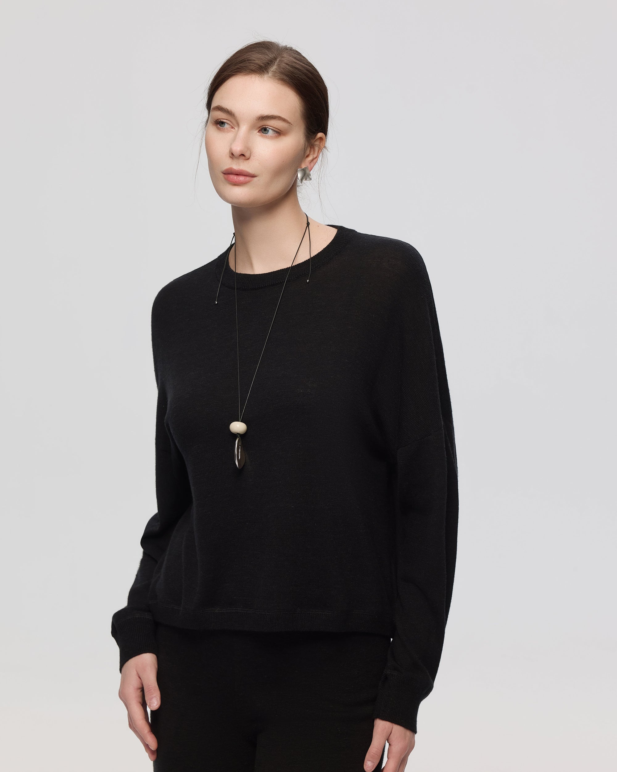 Model wearing Juana Nilo Knitted Hemp Crewneck in black merino–silk–hemp blend, styled for sustainable everyday wear.