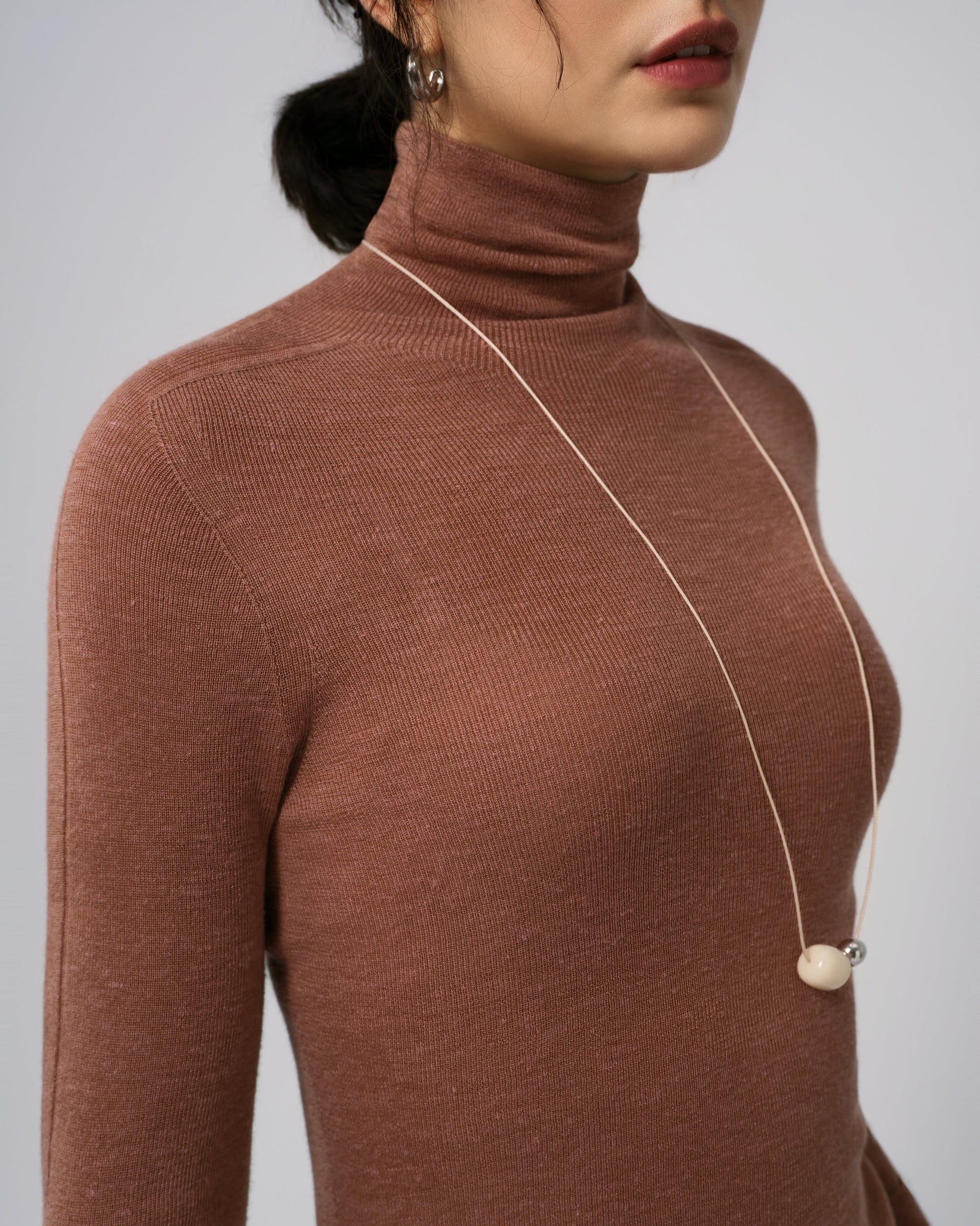 Detail shot of turtleneck collar, shoulder seam, and fine-gauge knit on Ossa Turtleneck (Mocha Mousse).